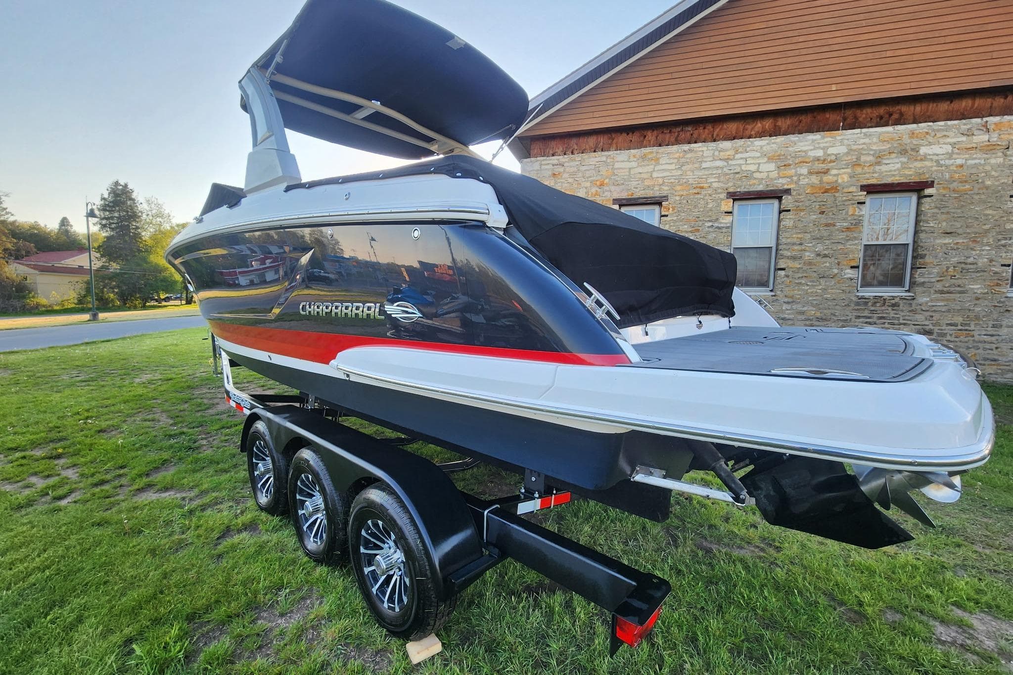 2019 Chaparral 297 SSX boat on trailer, parked on grass near stone building.