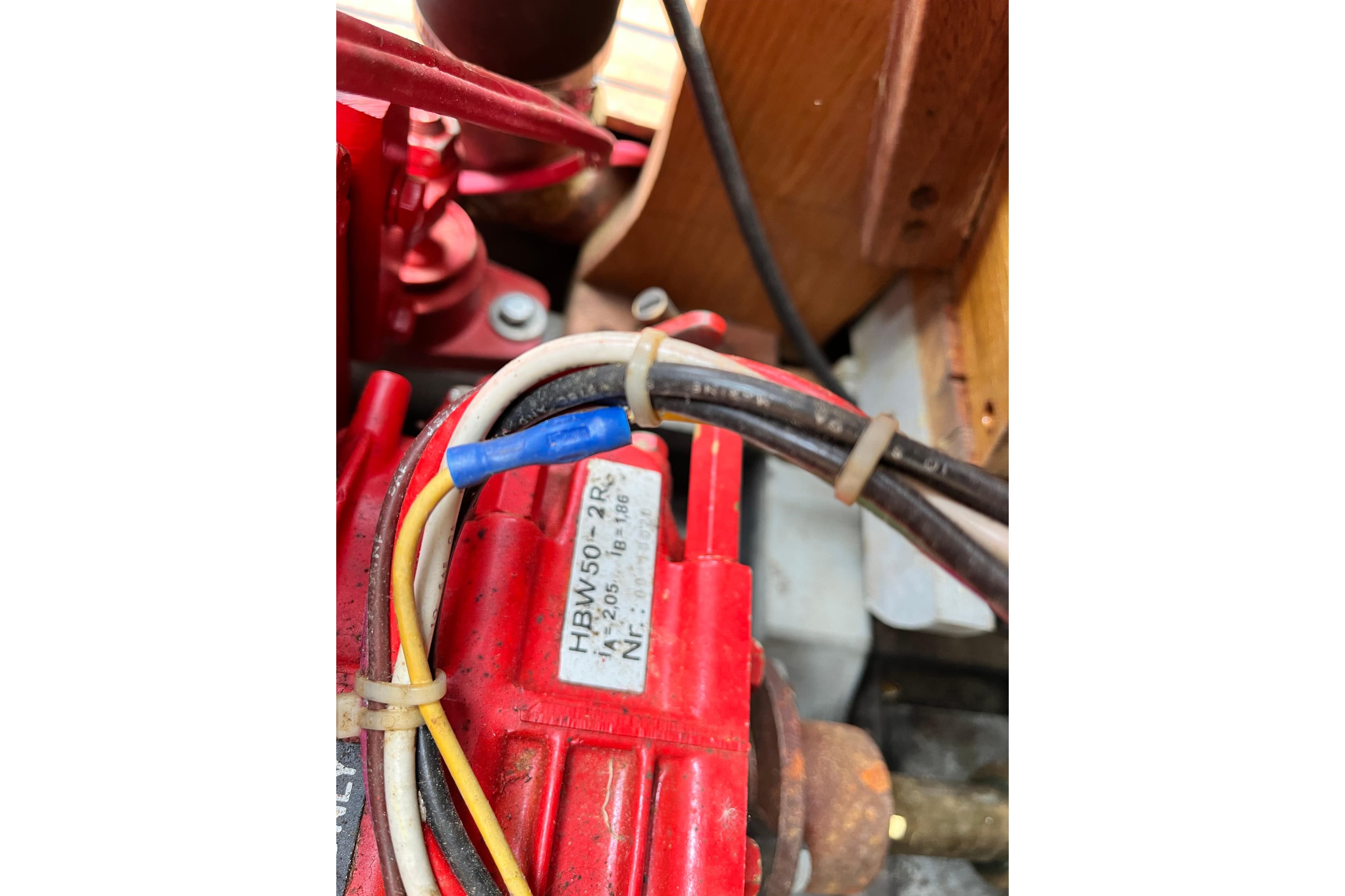 Close-up of a 1908 Outing launch engine component with visible wiring and label.