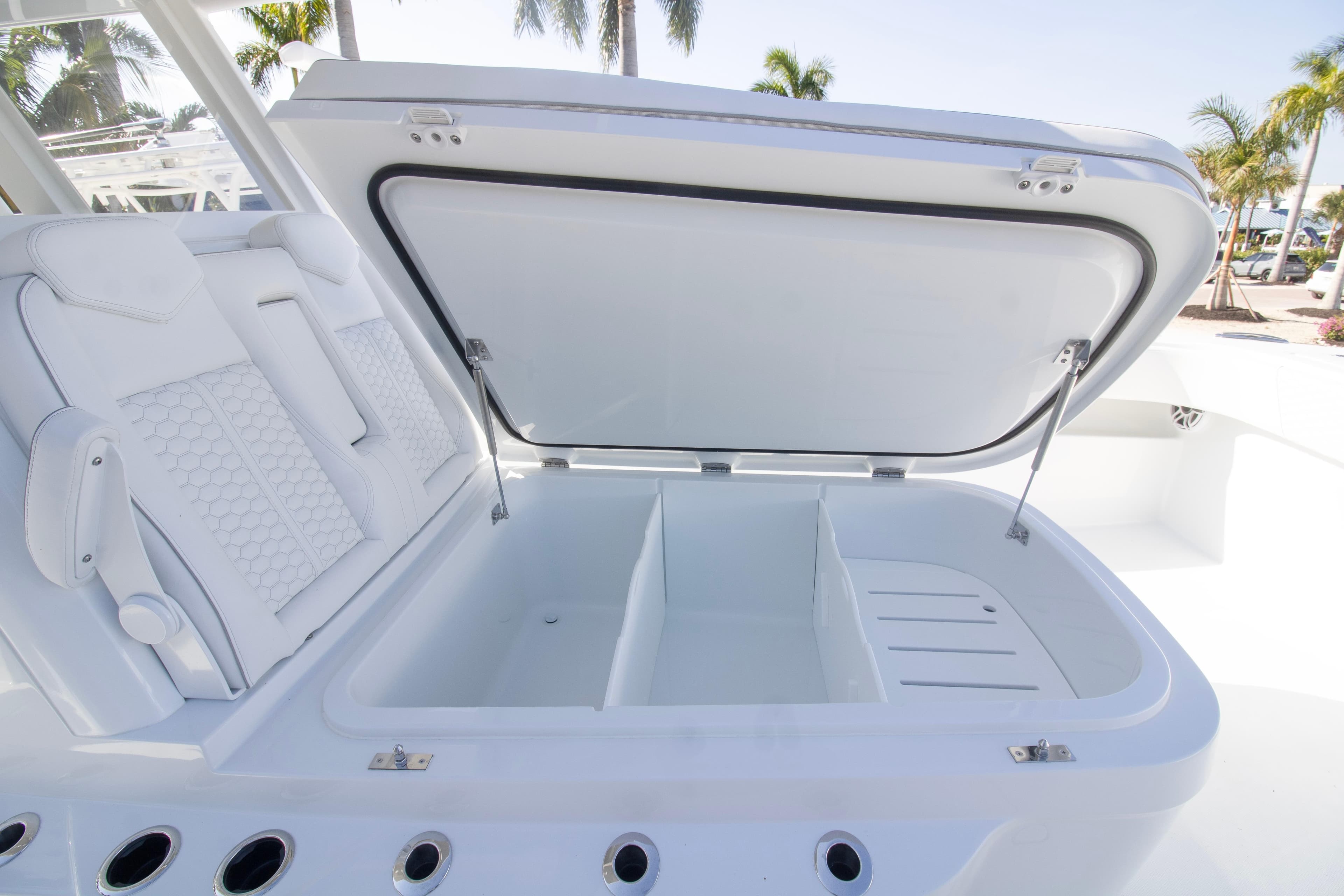 Open storage compartment on 2026 Invincible 36 Catamaran, featuring sleek white design and seating.