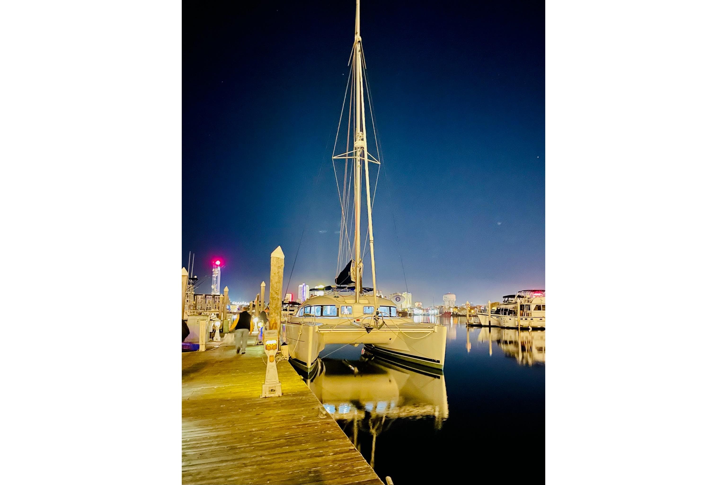 2008 Lagoon 380 S2 catamaran docked at night, reflecting on calm water.