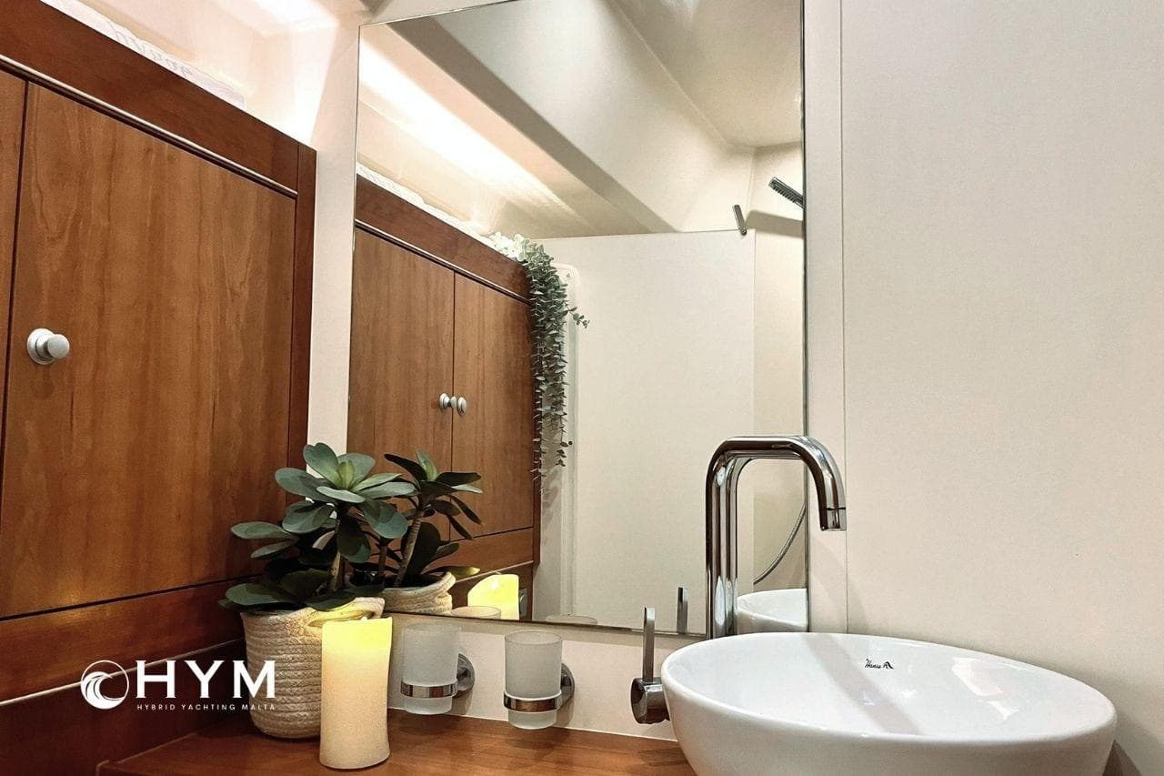 Luxurious bathroom interior of 2014 Hanse 575 yacht with modern sink and wooden cabinetry.
