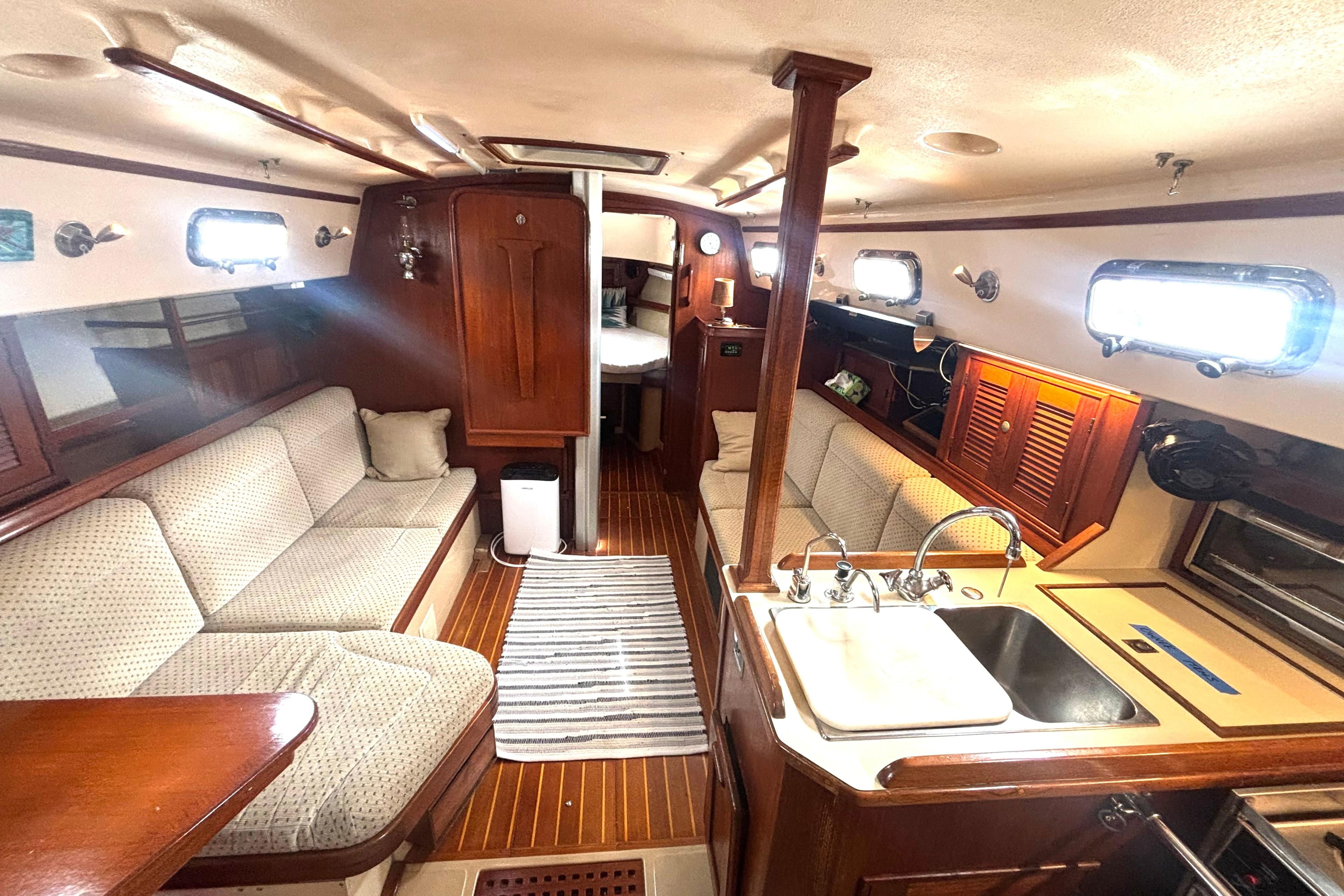 Interior of a 1995 Island Packet 37 sailboat, featuring cozy seating and a compact kitchen.