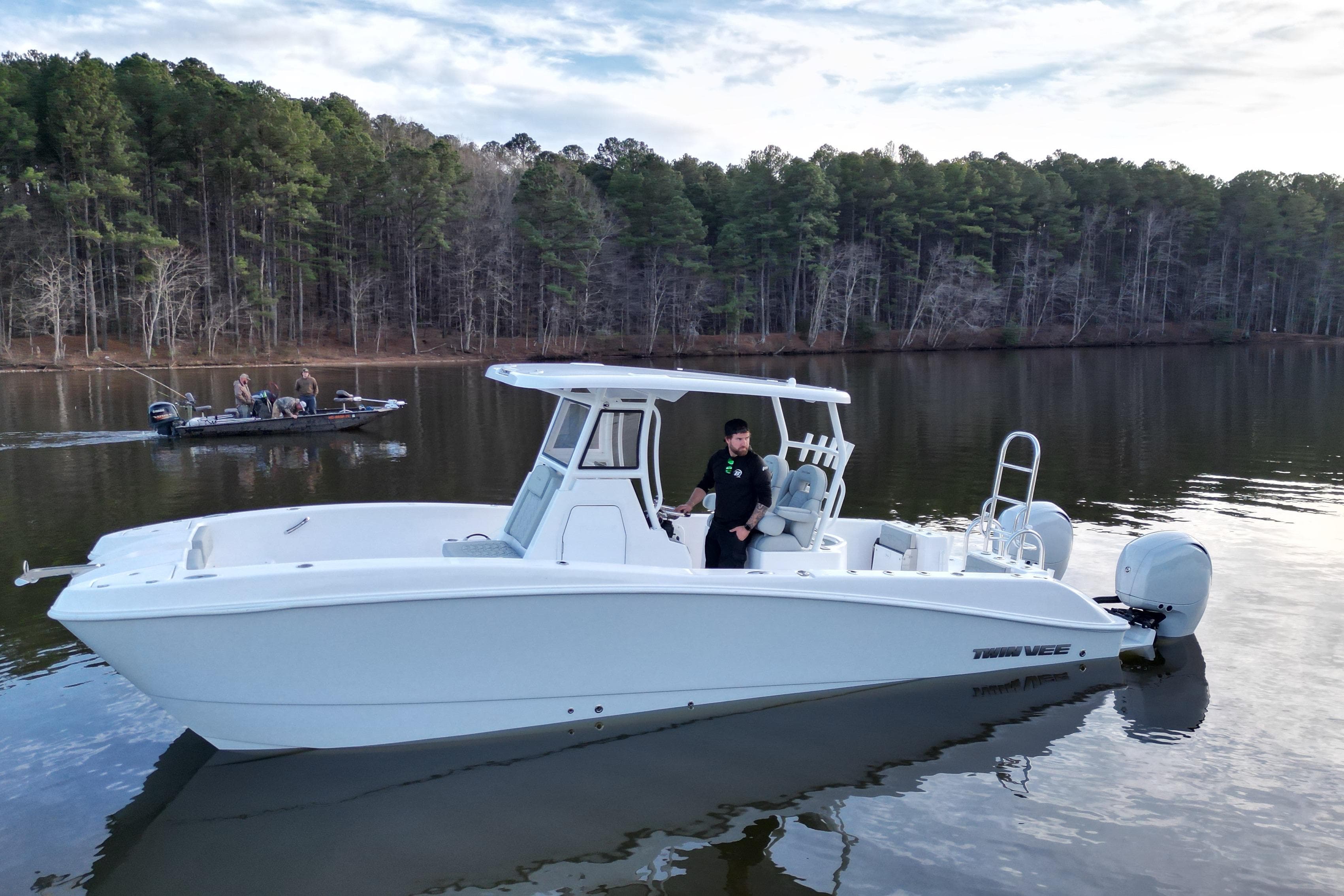 2023 Twin Vee 260 GFX CC boat on a calm lake with forested background.
