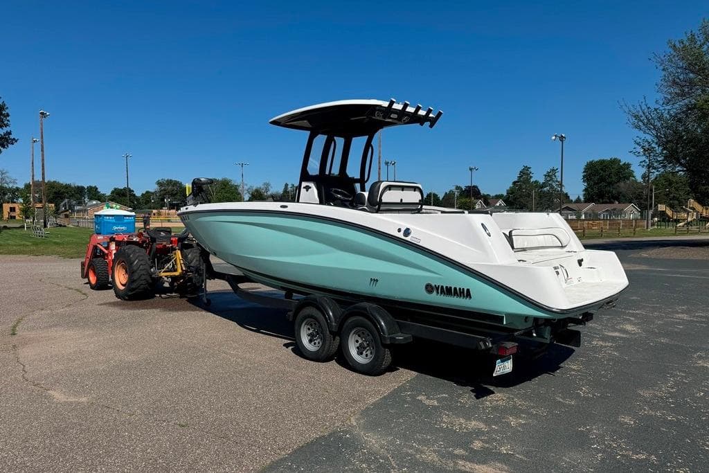 2023 Yamaha Boats 255 FSH Sport E on trailer, parked outdoors under clear blue sky.