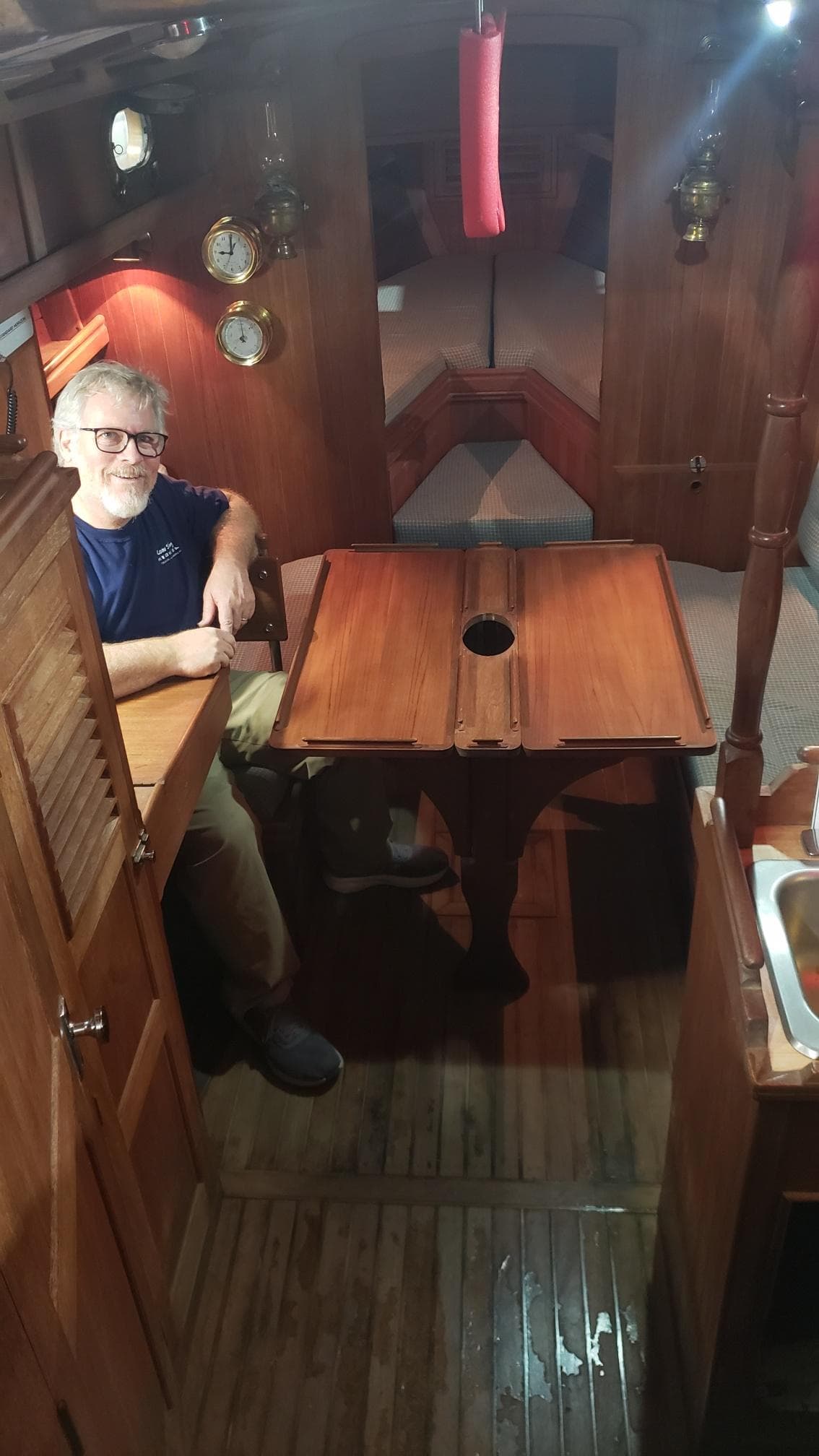 Interior of a 1981 Shannon 28 sailboat with wooden furnishings and a person seated at a table.