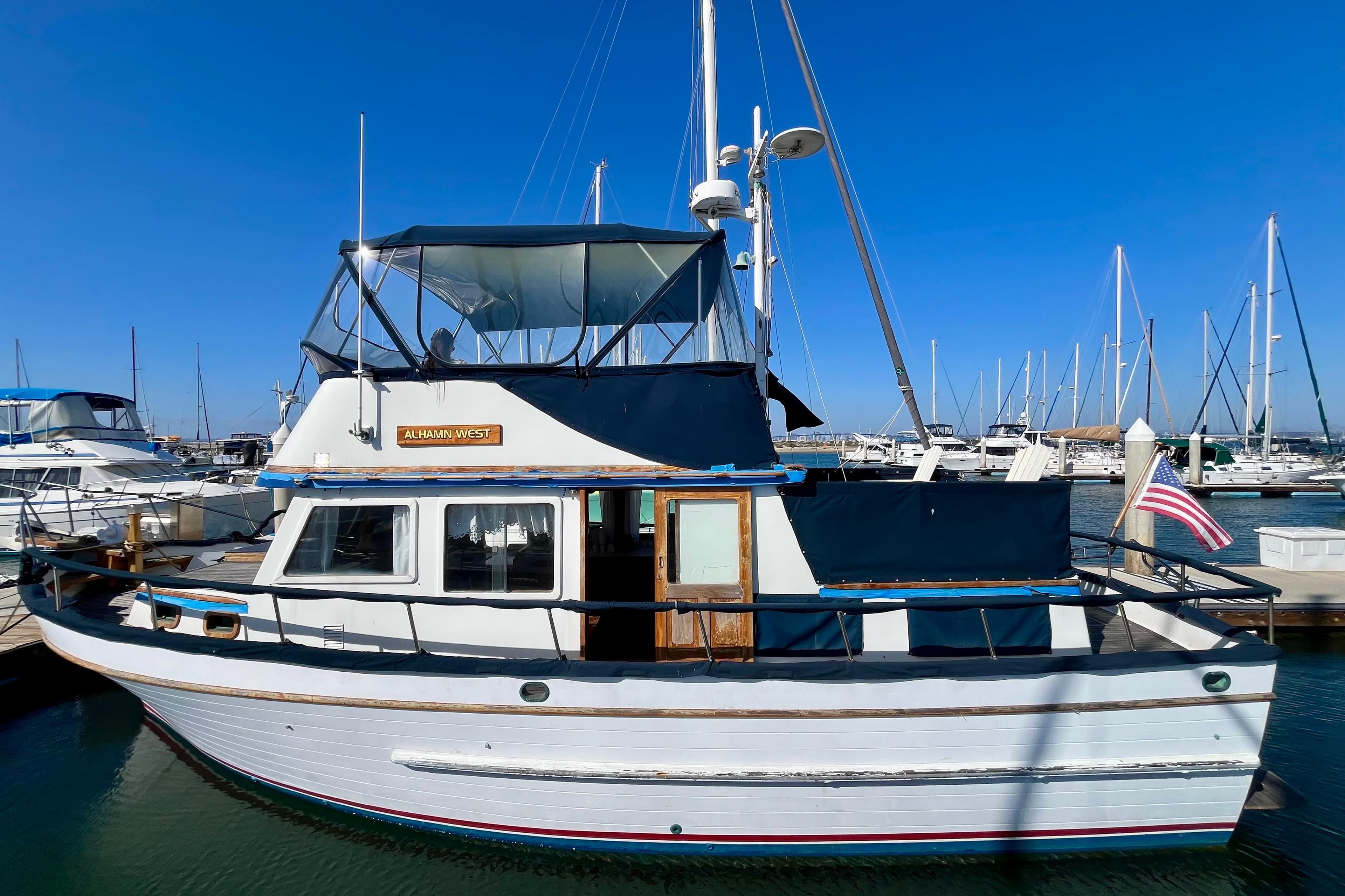 Vintage 1978 C&L 37 boat docked in a marina under clear blue skies.