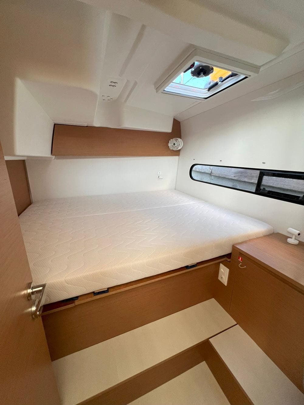 2025 Excess 11 yacht cabin with bed, window, and wooden interior.