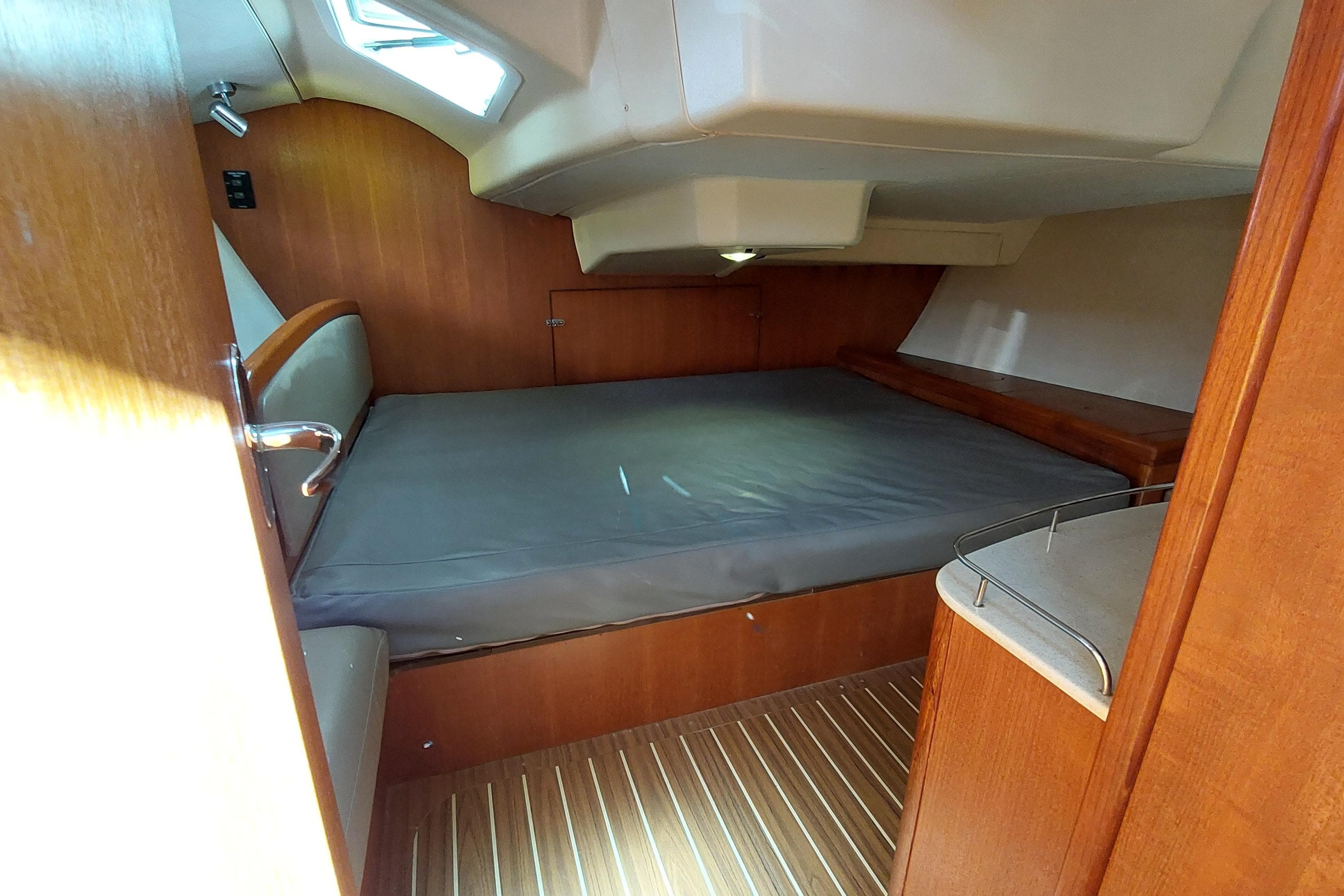 Cozy cabin interior of 2005 Hunter 38 sailboat with wooden finishes and comfortable bedding.