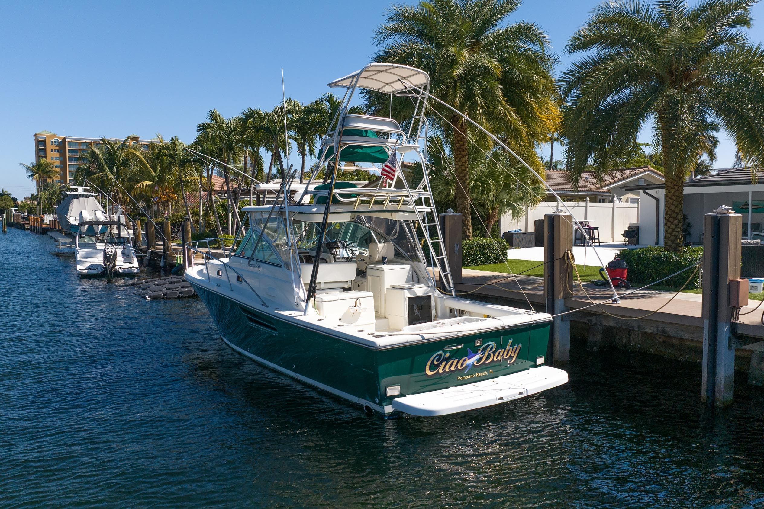 2000 Pursuit 3400 Express boat docked by palm trees in a sunny marina.