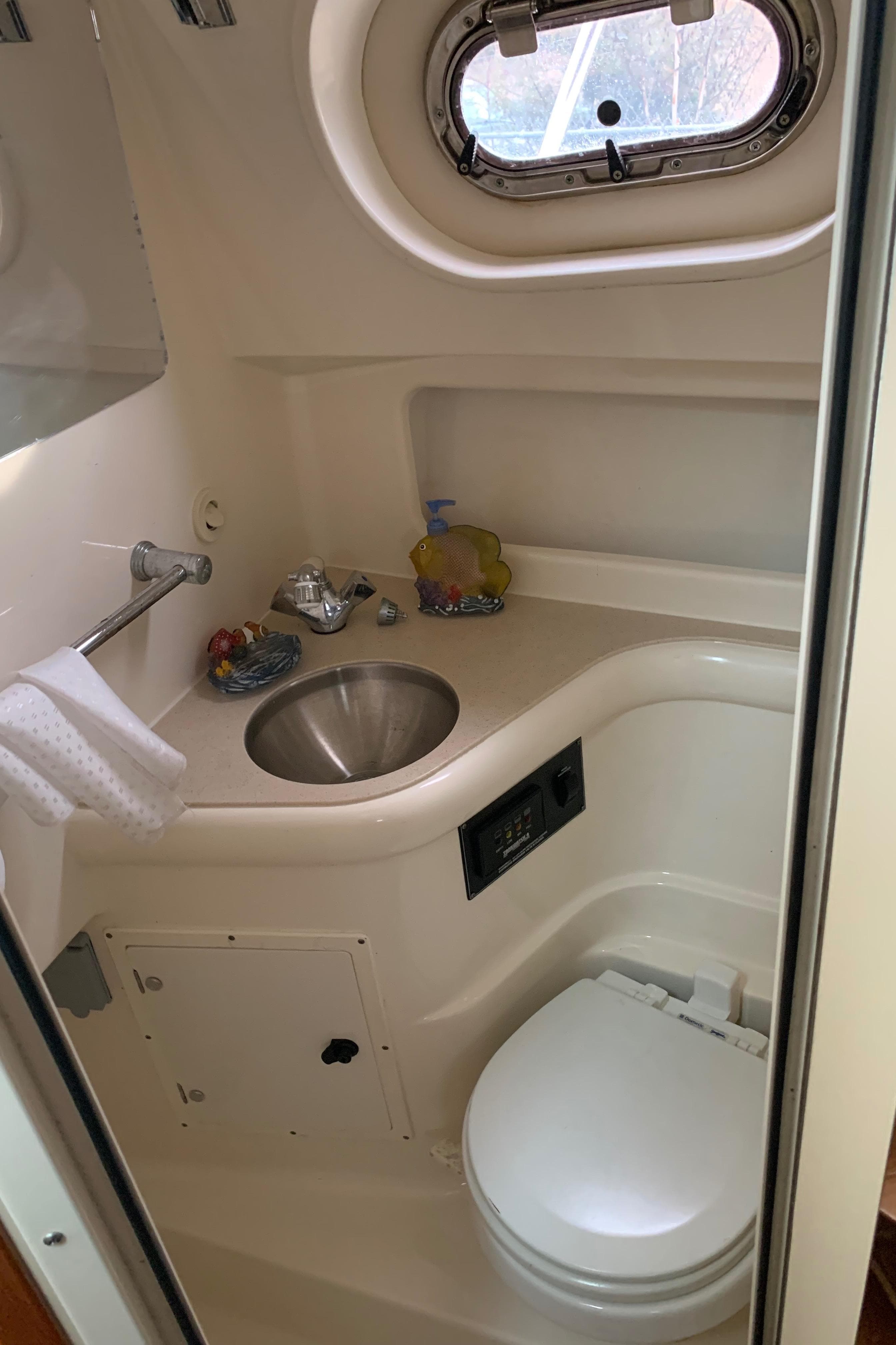 2007 Pursuit OS 335 boat bathroom with sink, toilet, and porthole window.