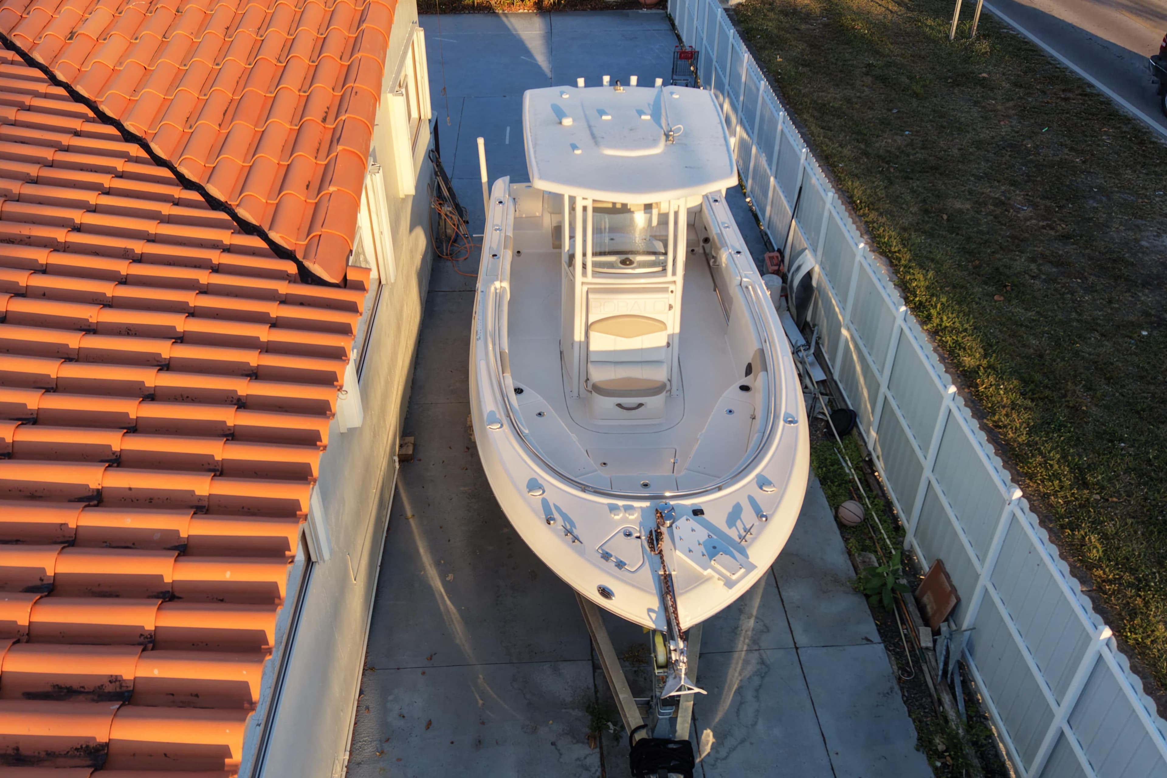 2018 Robalo R242 Center Console boat parked beside a house with a tiled roof.