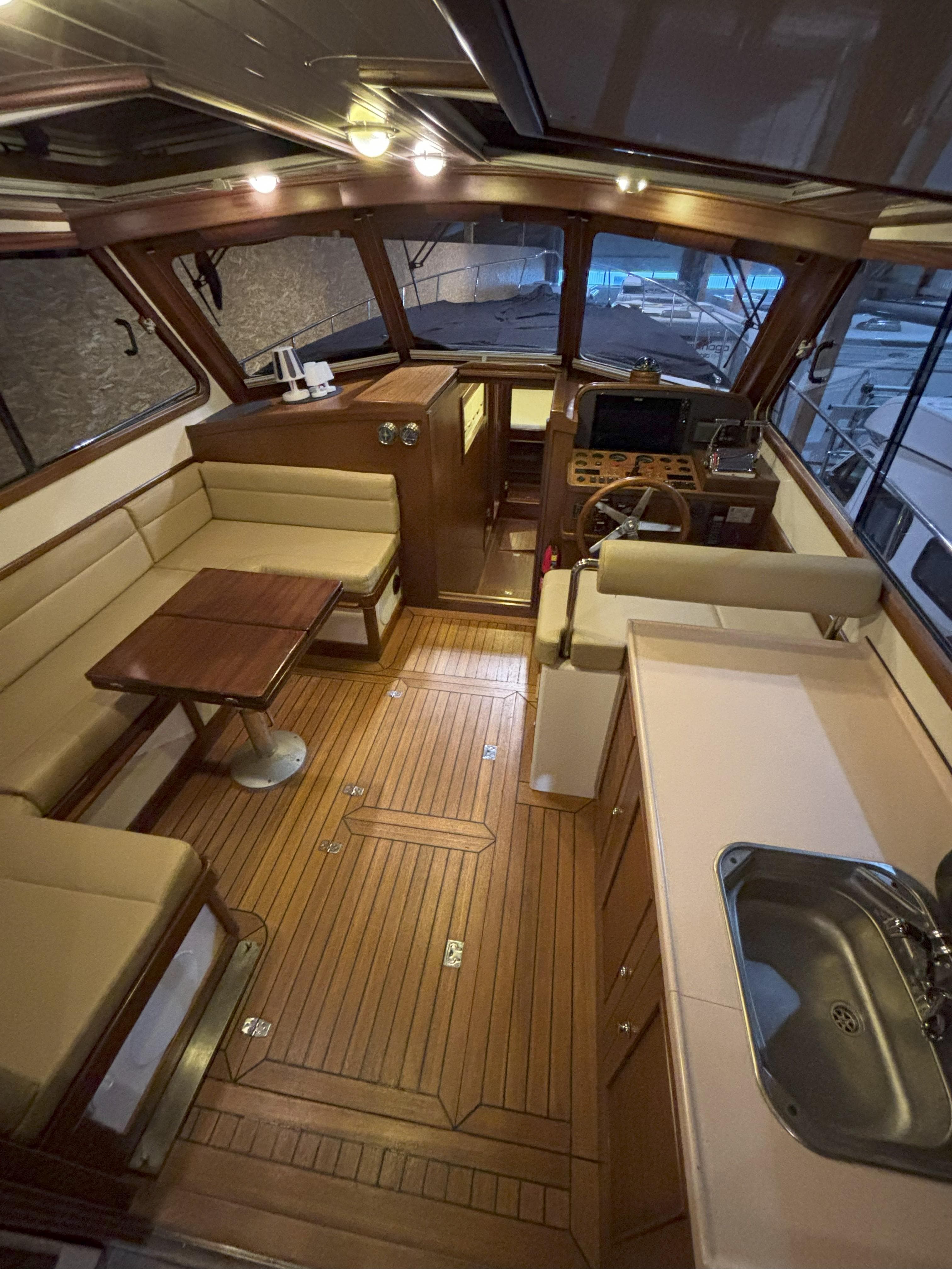 Interior of a 2003 Rapsody 48 yacht with wooden flooring, seating, and a compact kitchen area.