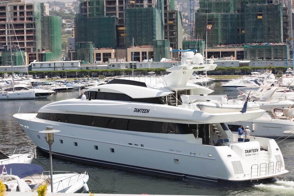 Luxury yacht Trident 127, 1998 model, docked in a marina with cityscape background.