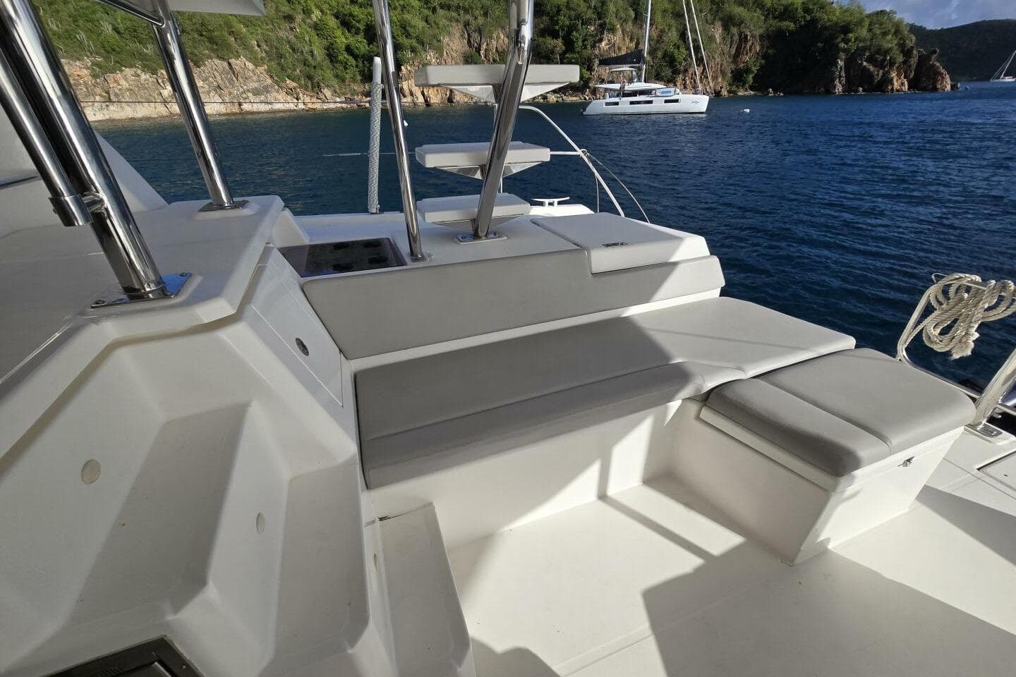Luxury Leopard 50 yacht deck with seating, overlooking serene blue waters and lush coastline.