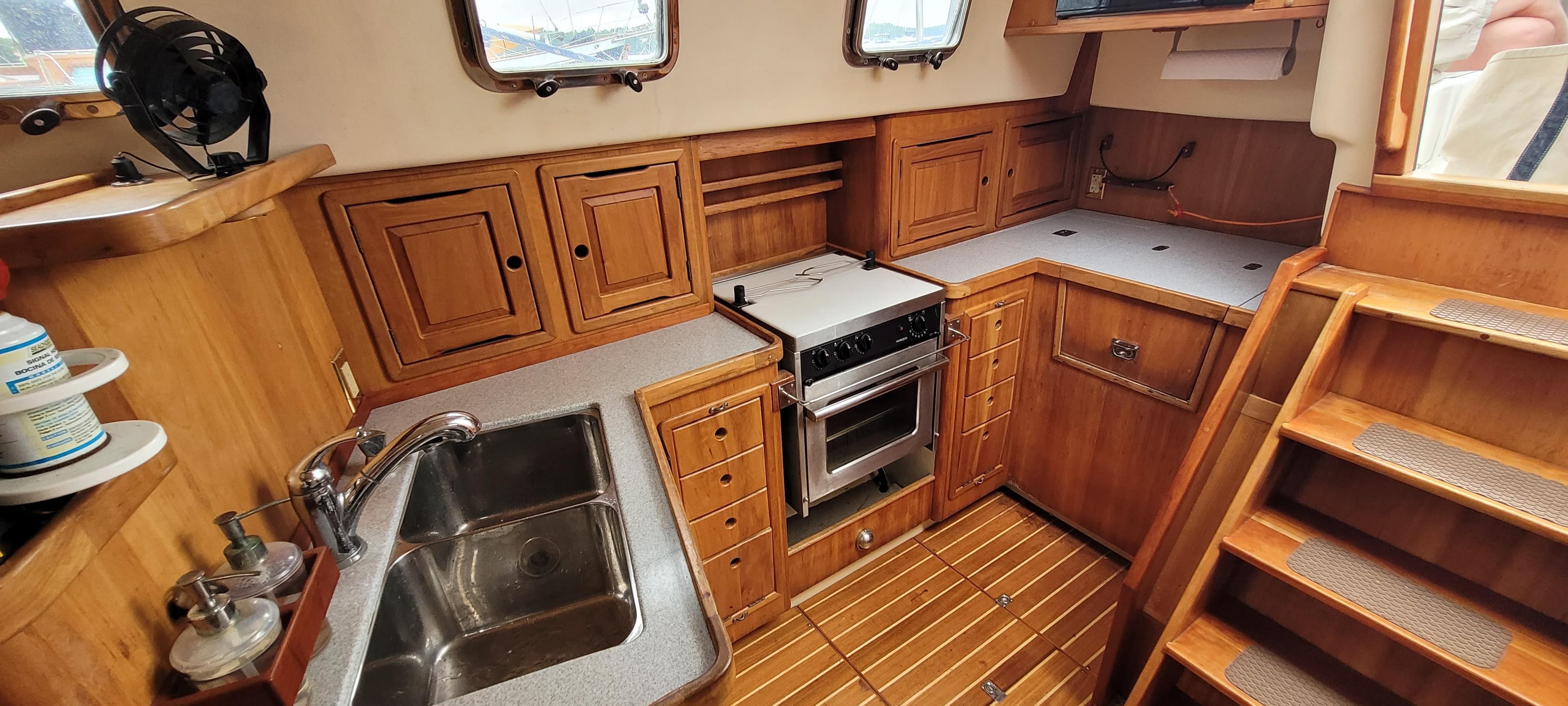1997 Saga 43 yacht kitchen with wooden cabinetry, stainless steel sink, and compact stove.