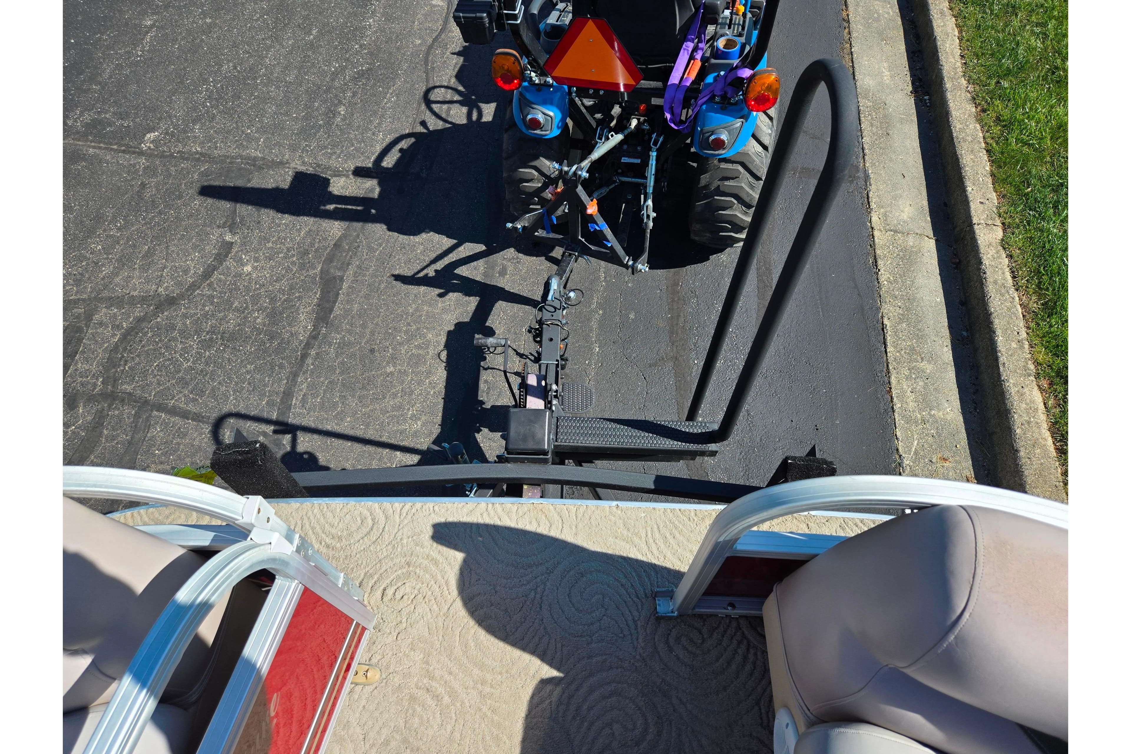 2014 Sun Tracker Party Barge 20 DLX hitched to a blue tractor on pavement.