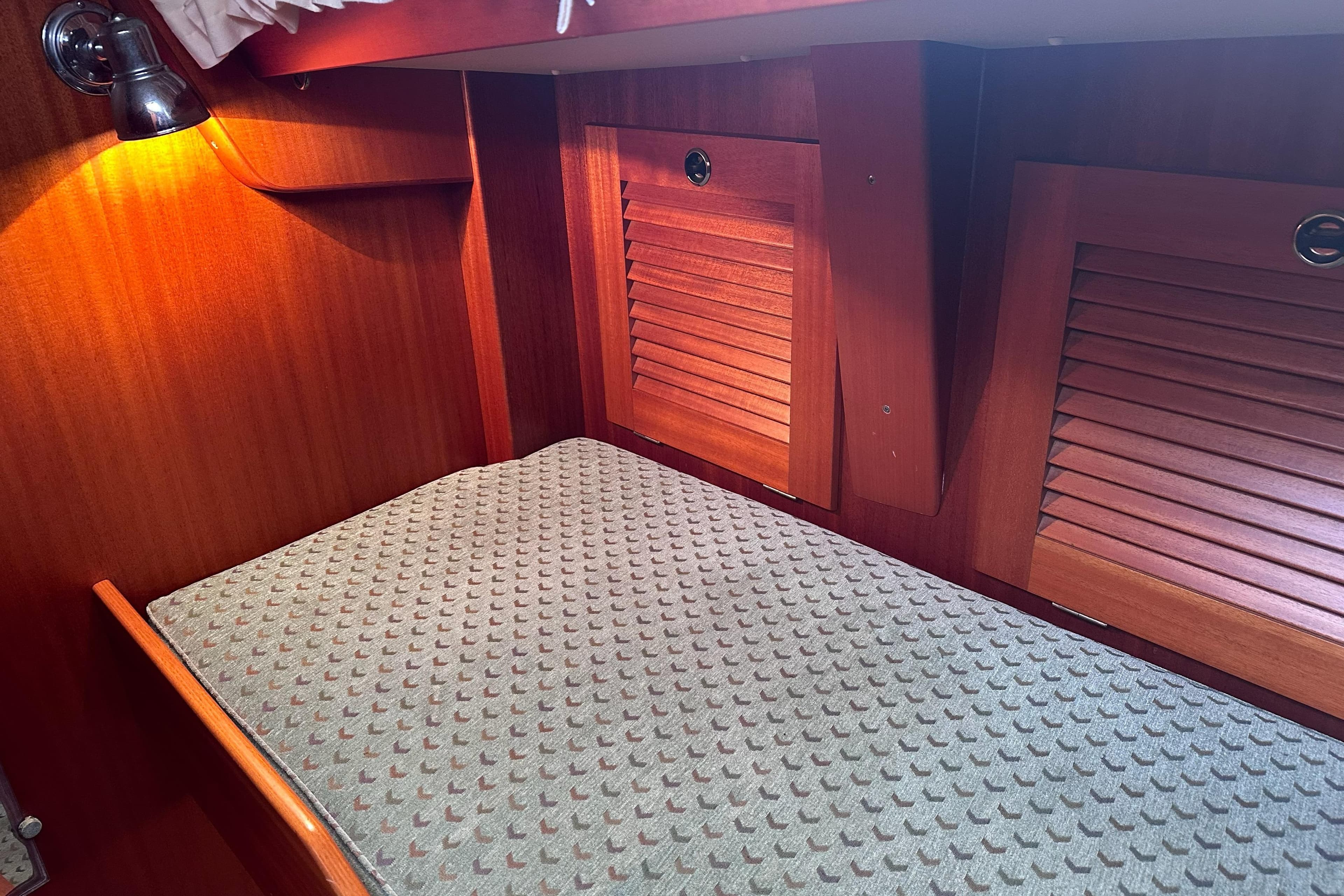 Cozy cabin interior of 2000 Hallberg-Rassy 46 yacht with wooden paneling and lighting.
