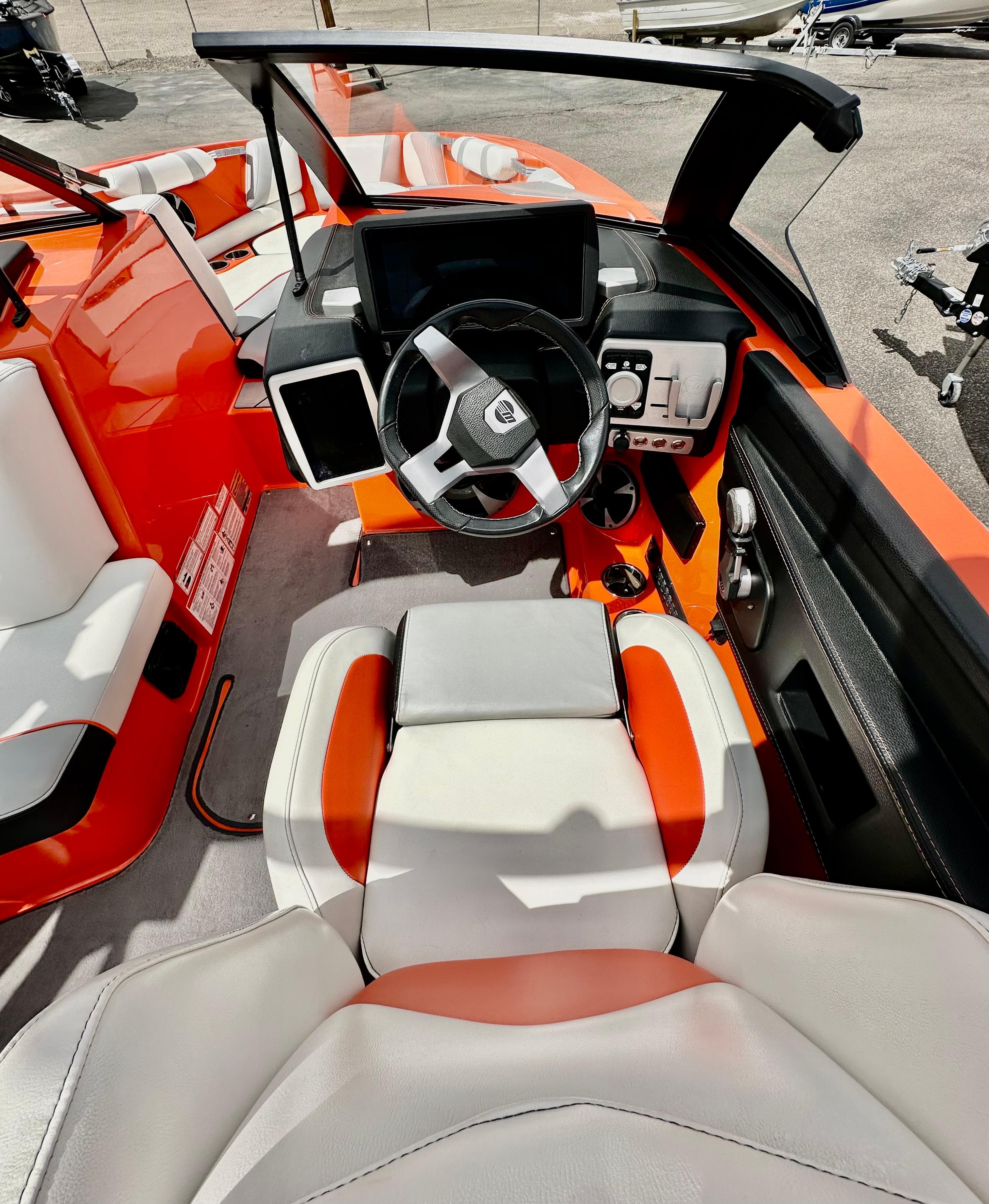 2020 Malibu 21VLX boat interior with orange and white seating, modern dashboard, and steering wheel.