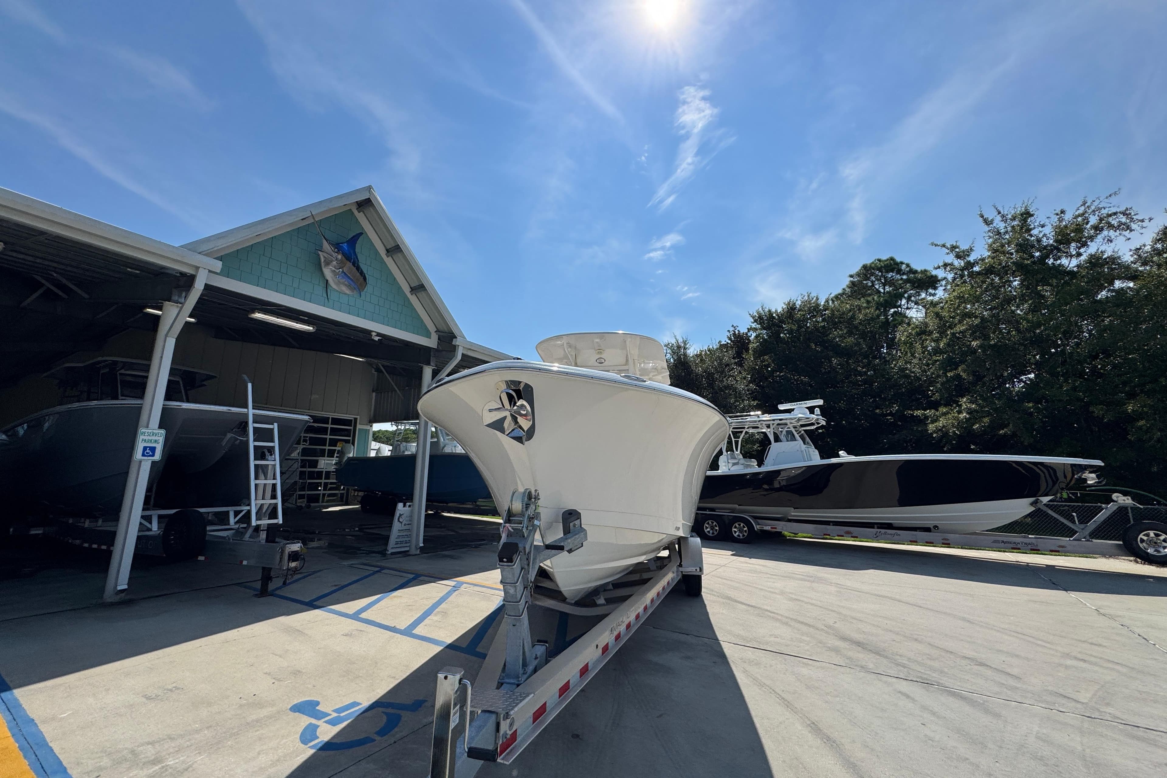 2024 NauticStar 292 Legacy boat on trailer at marina under clear blue sky.