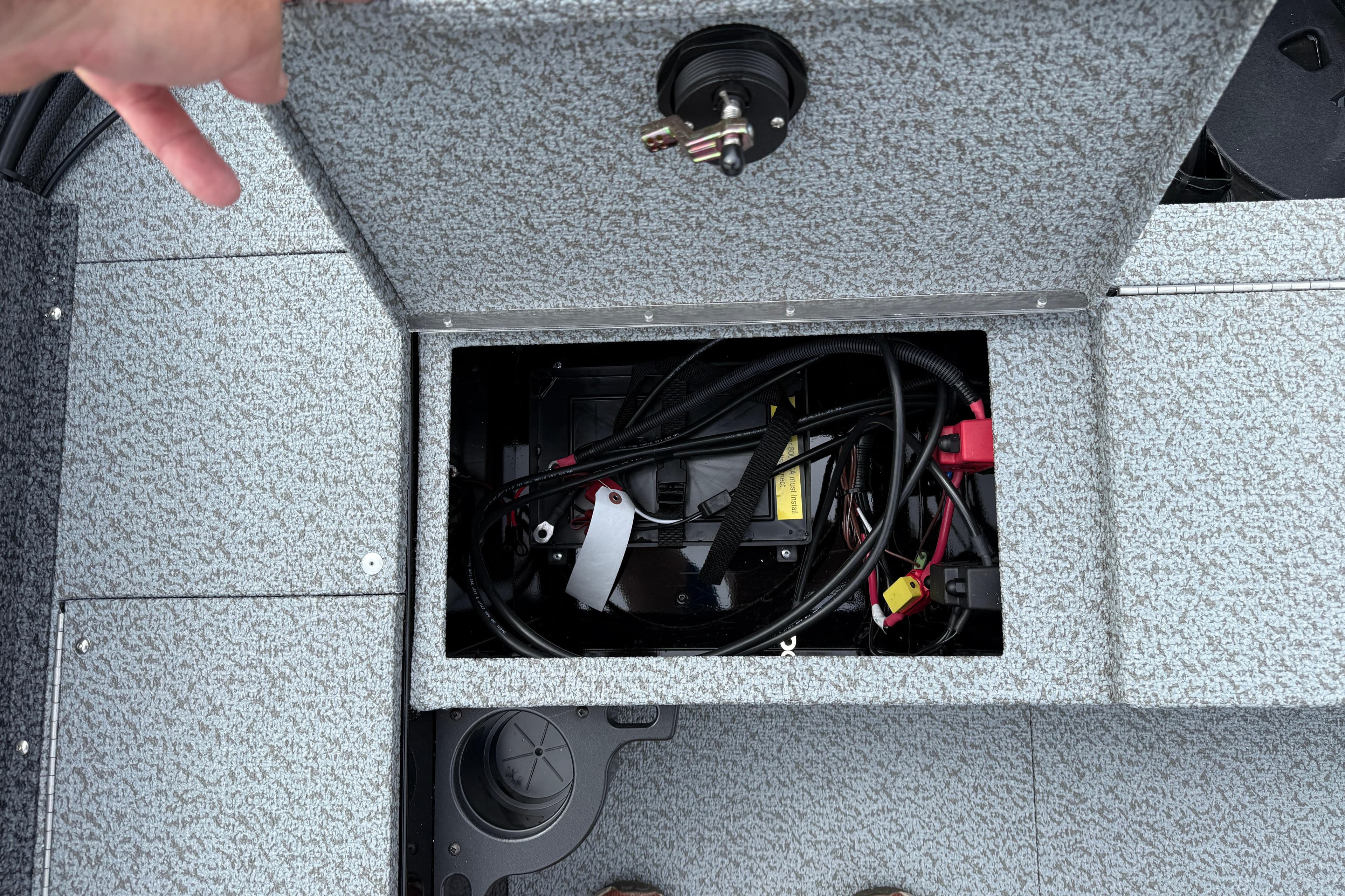 Open storage compartment in 2026 Lund 1800 Explorer Sport boat, showing battery and wiring.