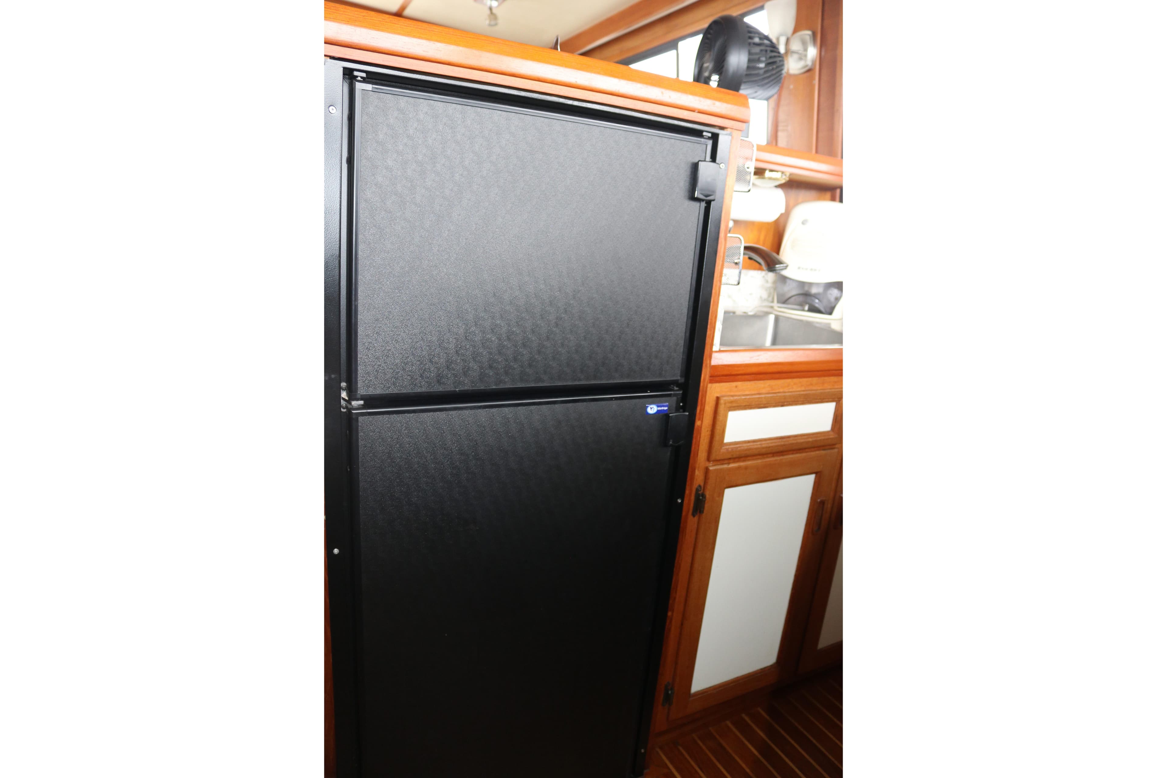 Black refrigerator in a wooden kitchen interior of a 1990 Cooper Prowler Sedan.