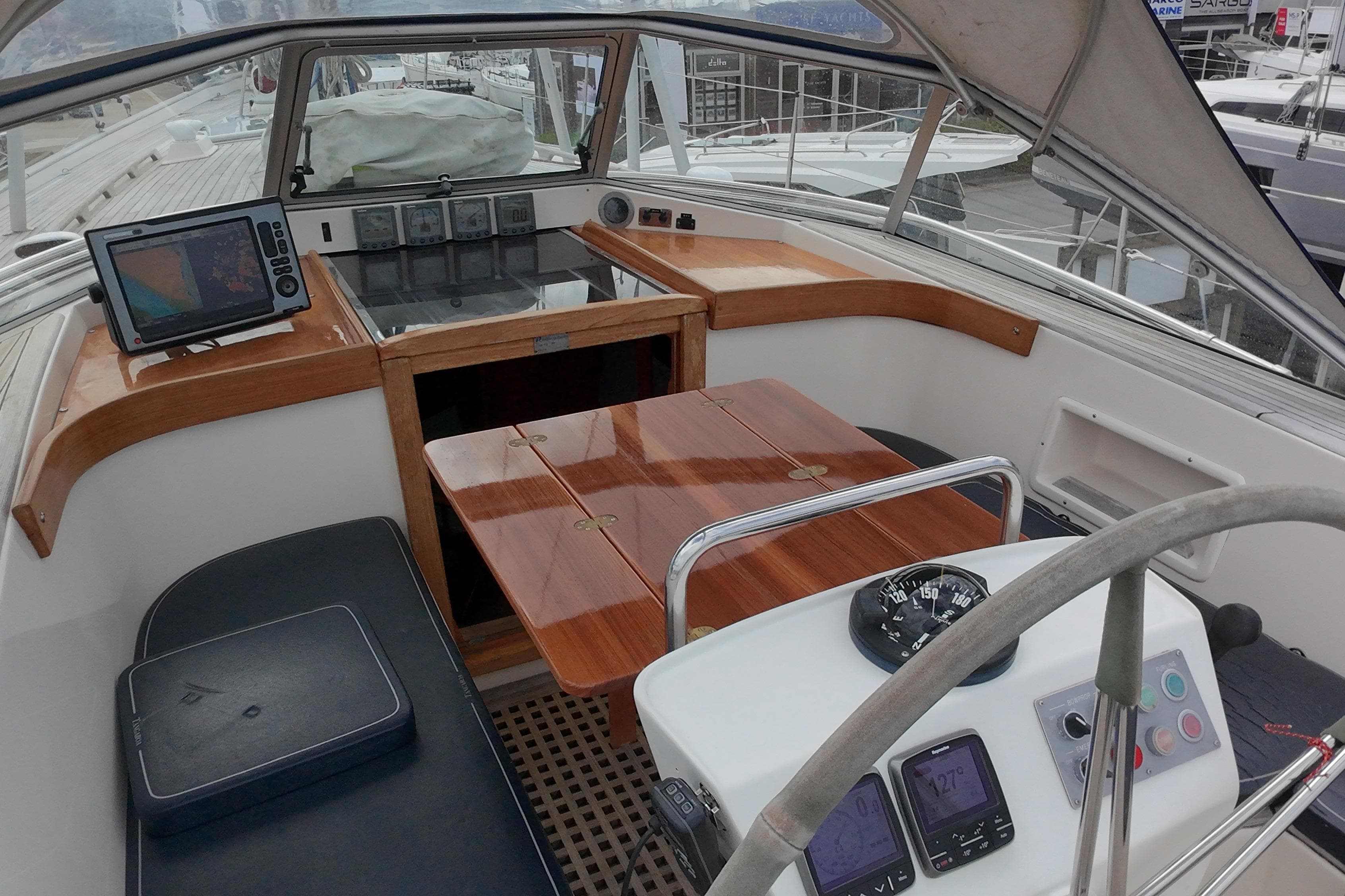 Cockpit of a 2000 Hallberg-Rassy 46 yacht with navigation equipment and wooden table.