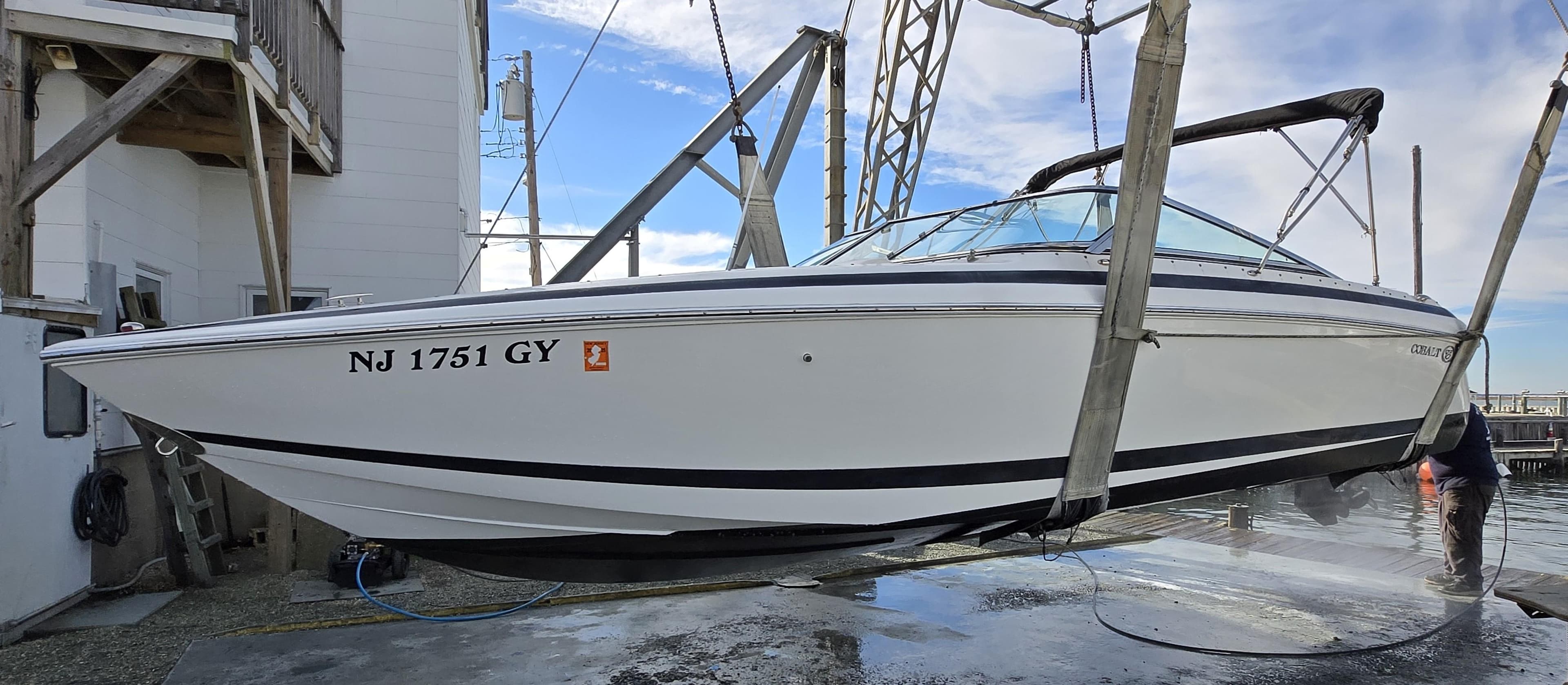 2006 Cobalt 262 boat suspended on a lift, side view, with registration NJ 1751 GY.