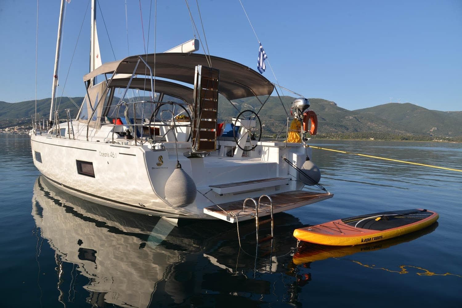 2019 Beneteau Oceanis 46.1 yacht docked with paddleboard, scenic mountain backdrop.