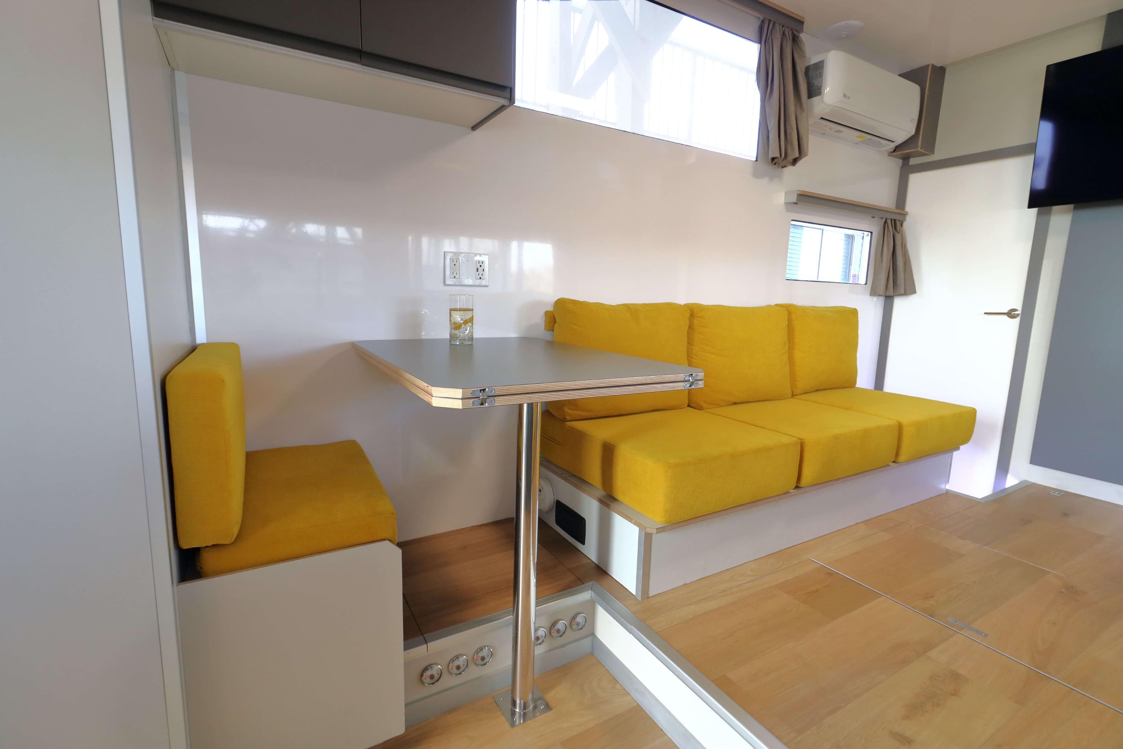 Modern Navisyo Homes NV.08 interior with yellow seating, compact dining area, and sleek design.