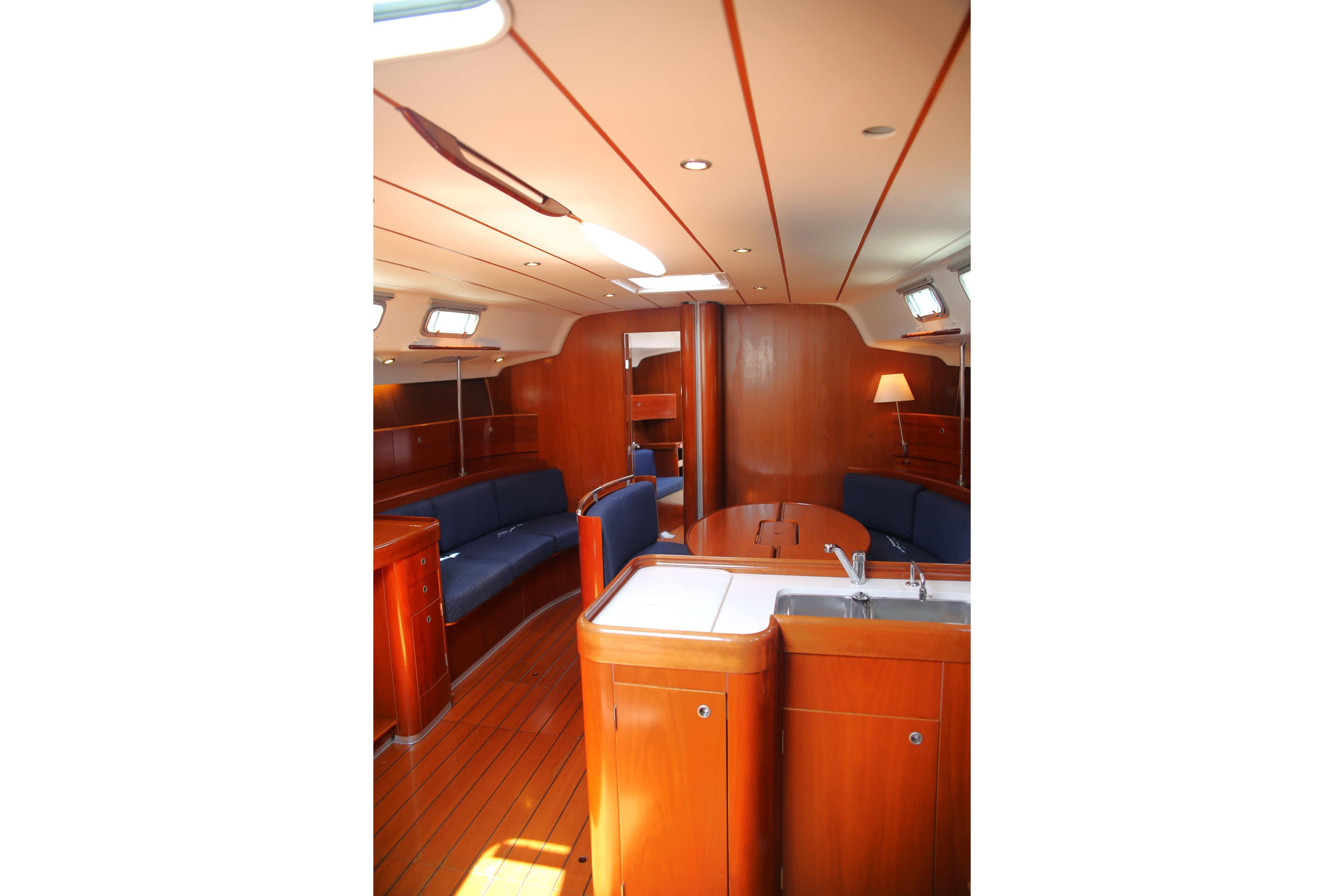 Interior of 2005 Beneteau First 47.7 yacht with wooden finish and blue seating.