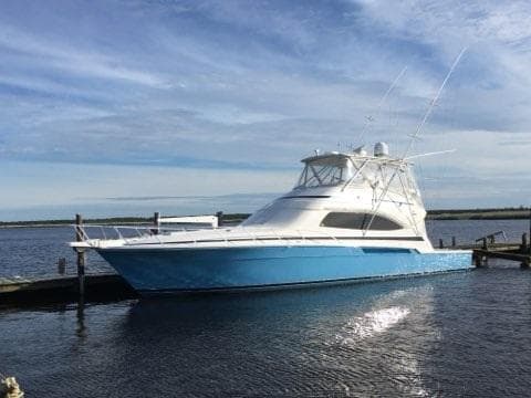 2007 Bertram 570 Convertible yacht docked on calm water under a clear sky.