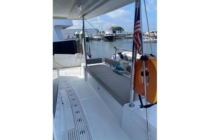 2023 Bali 4.2 yacht deck with seating, docked at marina, American flag displayed.