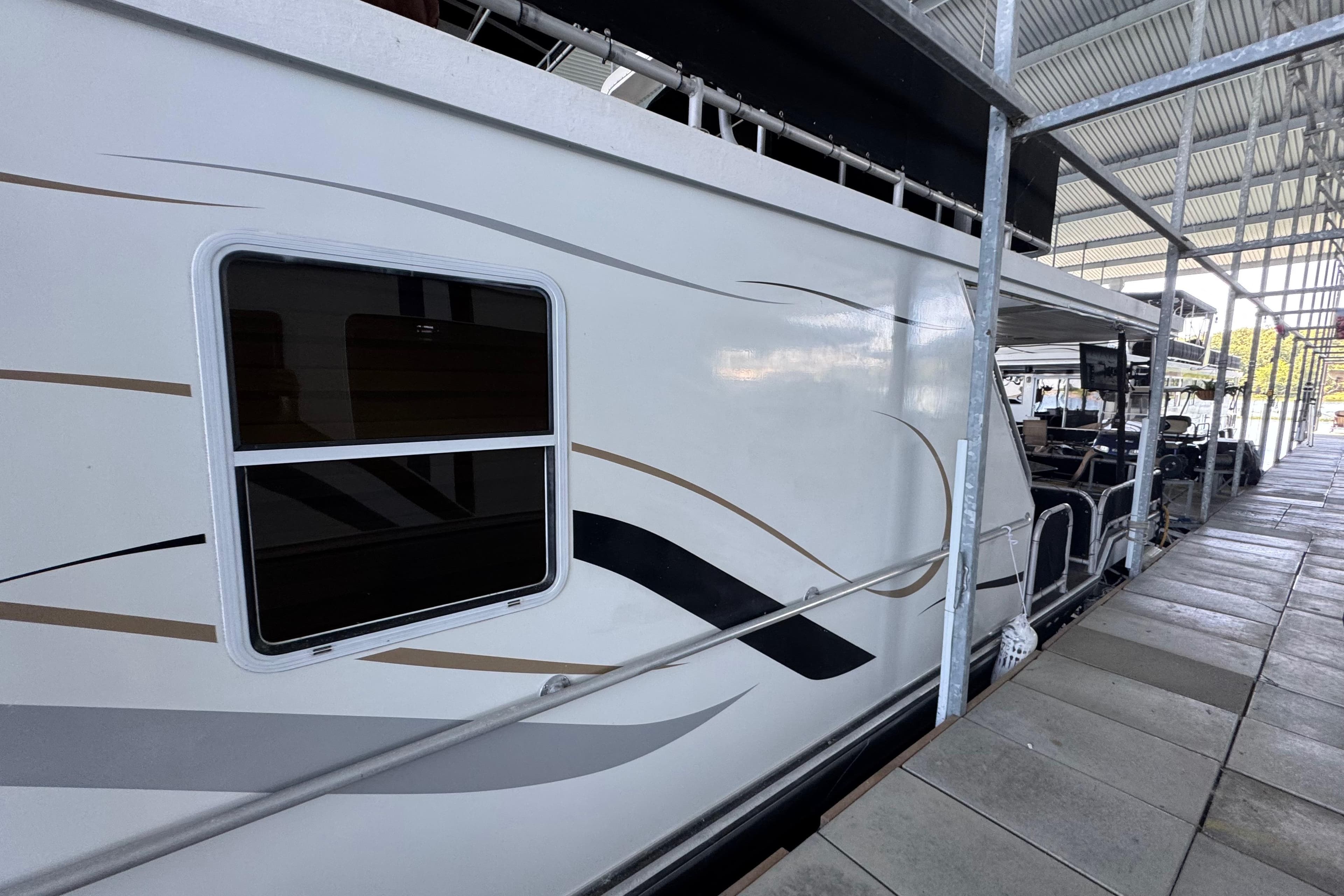2004 Starlite 65x16 houseboat docked under a covered marina.