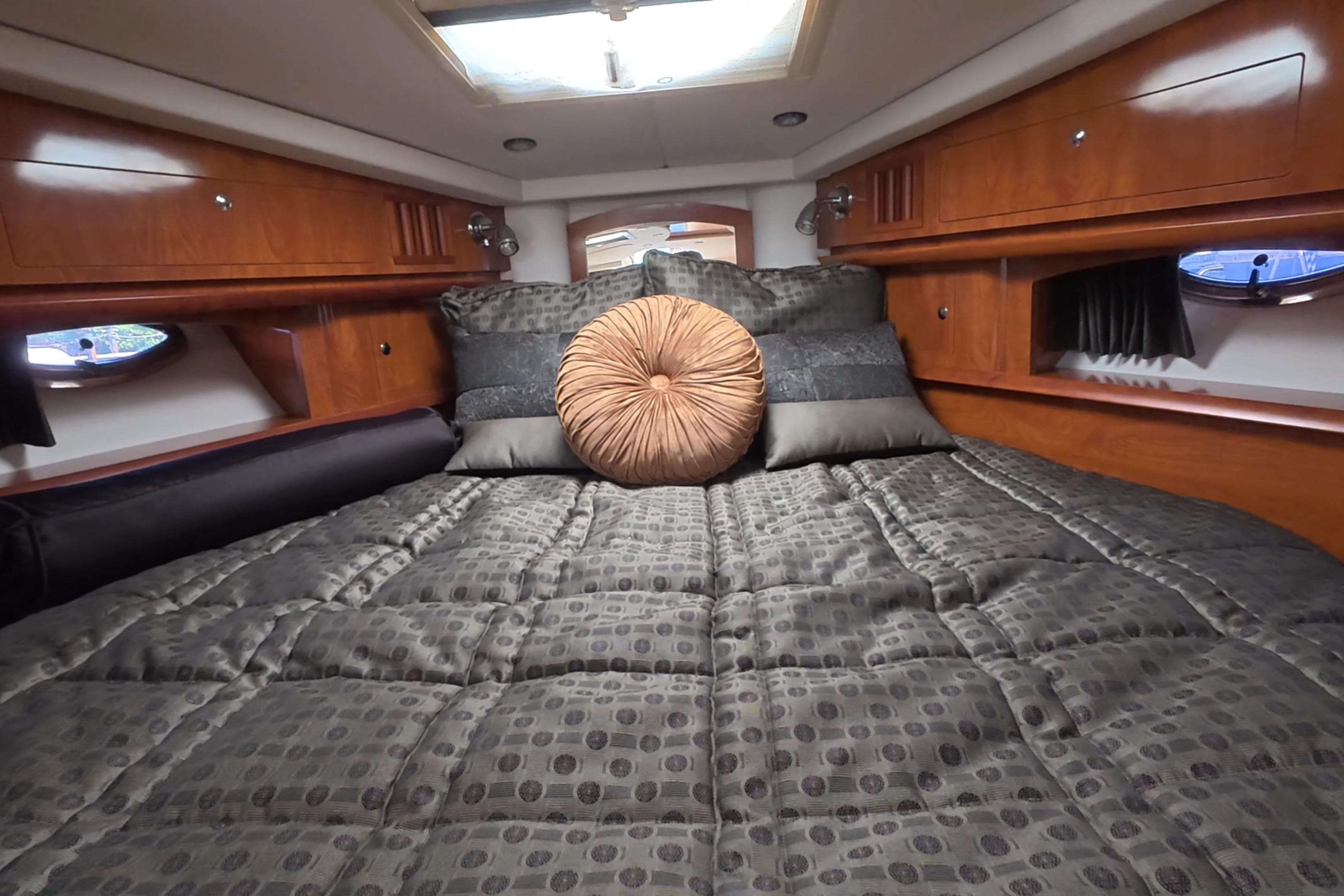 Luxurious cabin interior of 2008 Four Winns V358 yacht with plush bedding and wood accents.