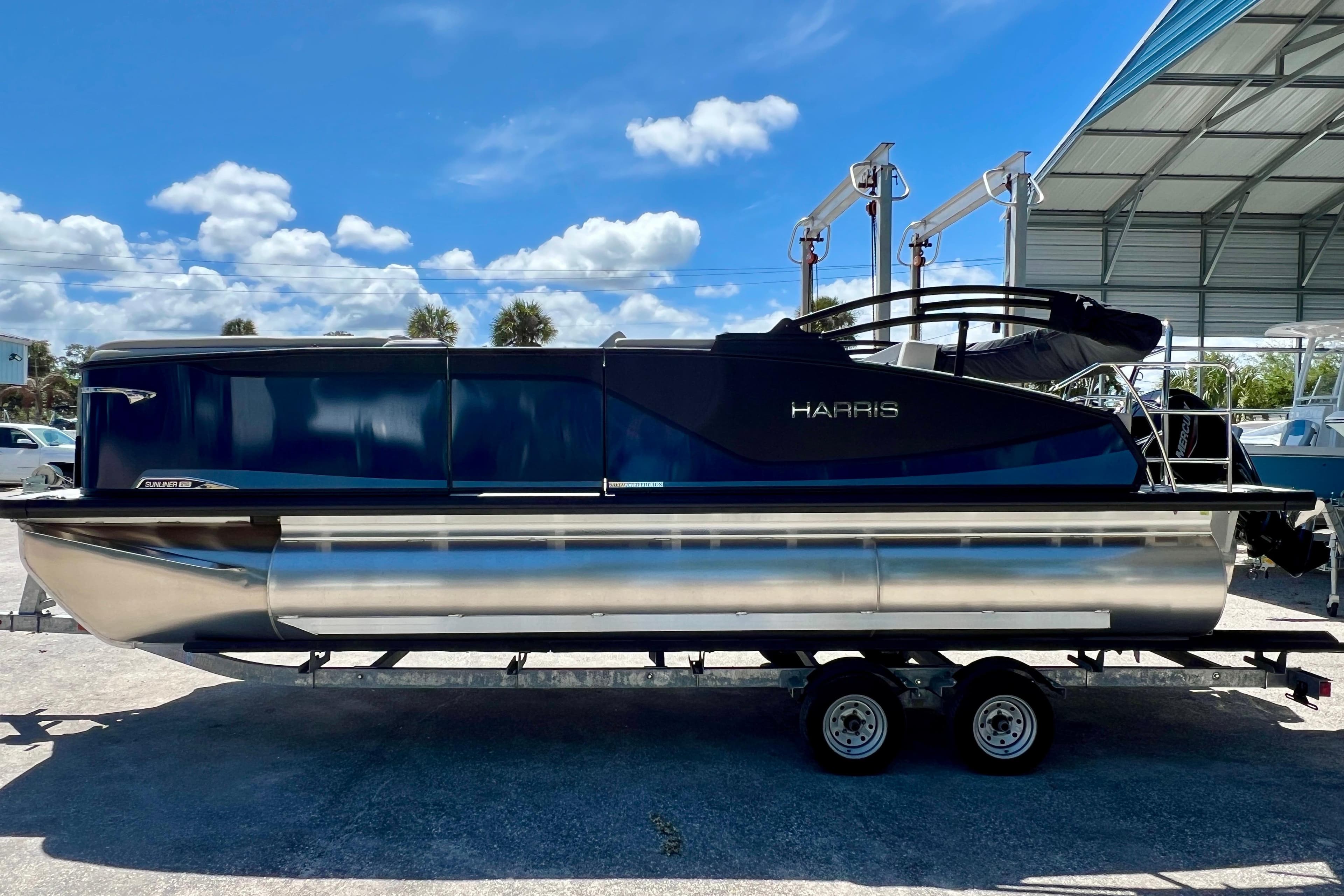 2026 Harris Sunliner 210 pontoon boat on trailer under blue sky.