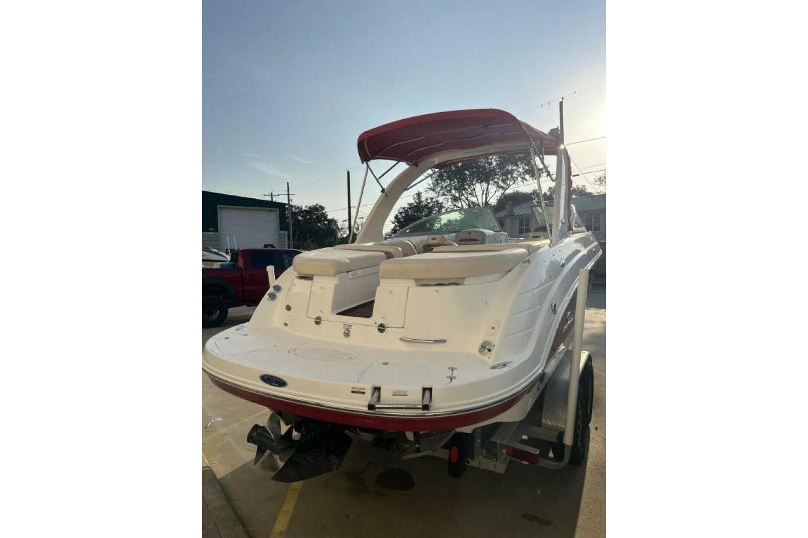 2006 Chaparral 256 SSi boat with red canopy, parked on a trailer, rear view.