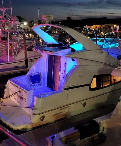 2004 Silverton 330 Sport Bridge yacht docked at night with blue LED lights.