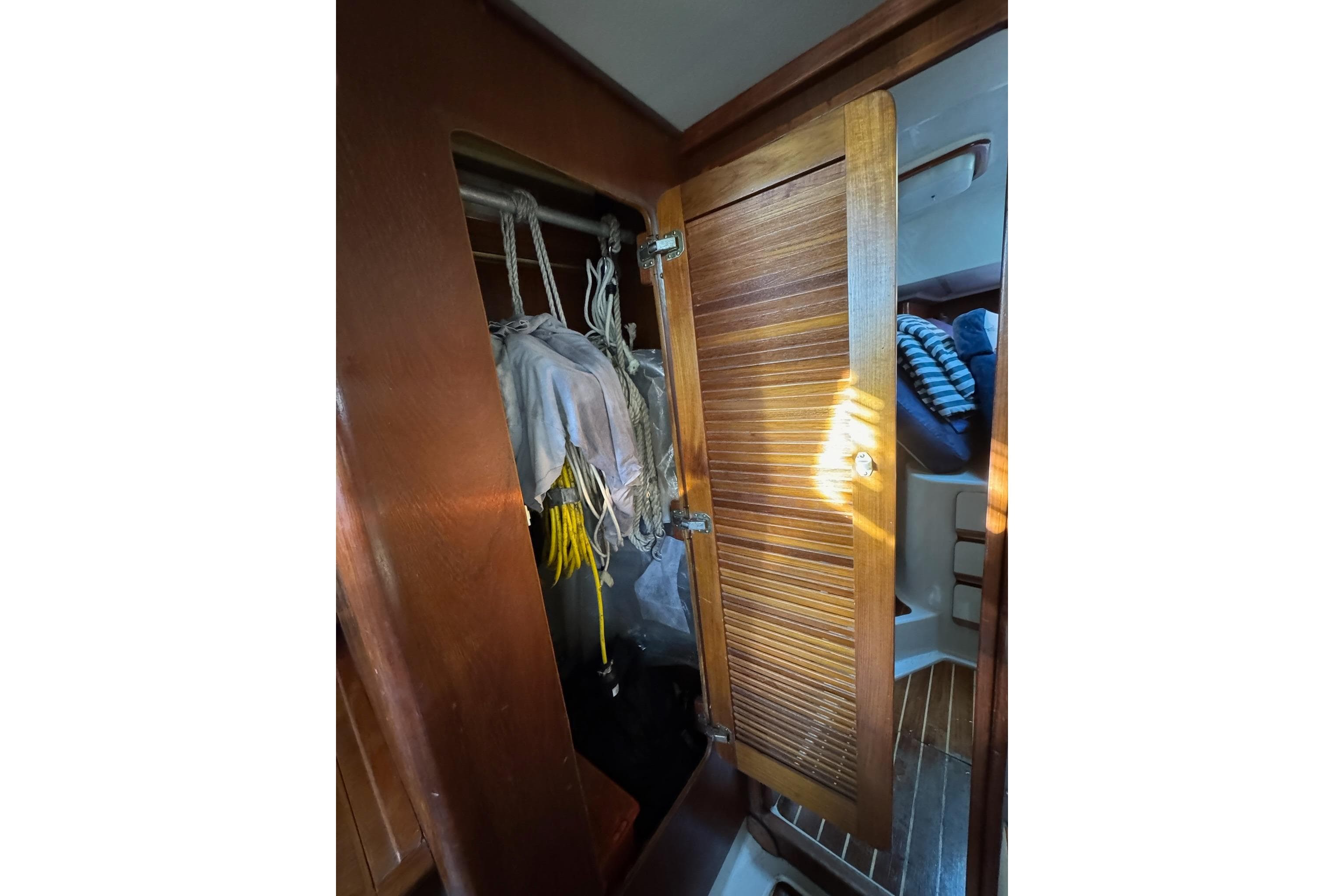 1987 Irwin 38 Mk II sailboat interior closet with wooden door and hanging ropes.