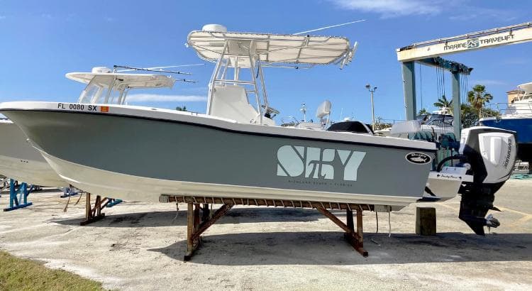 2021 Dusky 252 T boat on dry dock with "Sky" logo, sunny day.