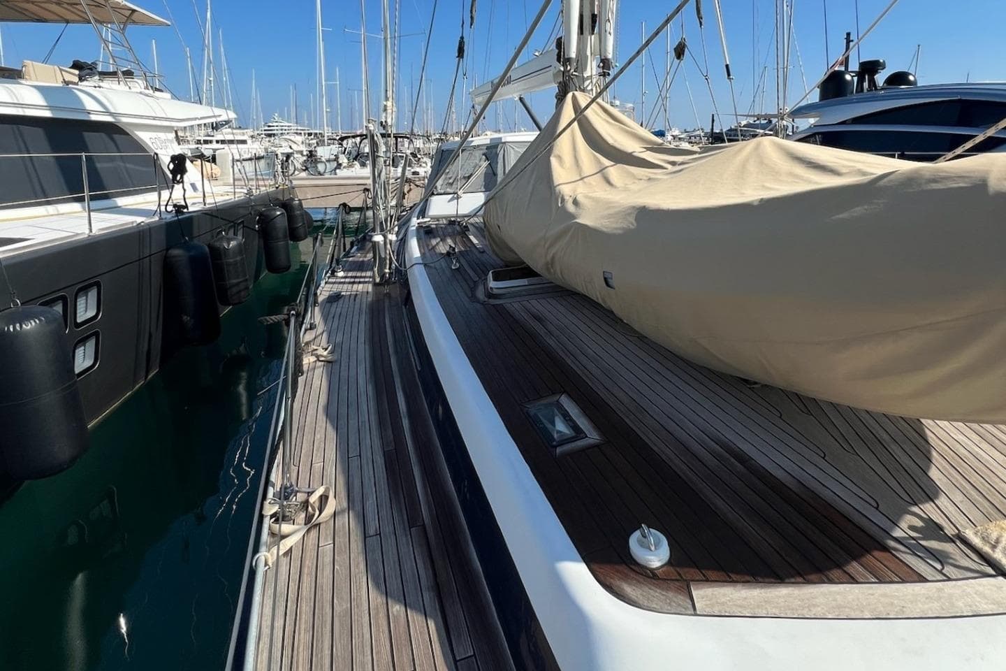 Luxury Jongert 2000s yacht from 1988 docked in a marina, showcasing sleek wooden deck.