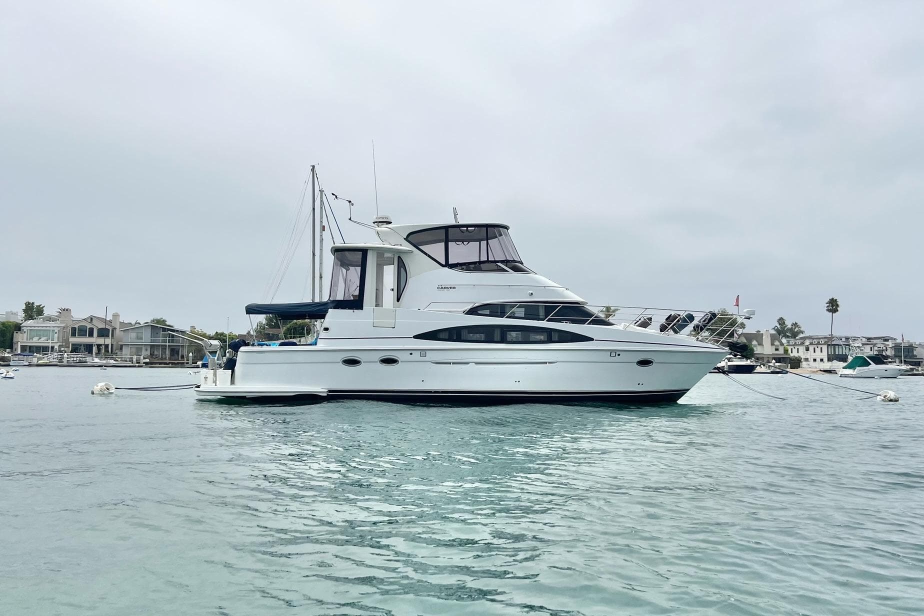 2003 Carver 444 Cockpit Motor Yacht on calm water, overcast sky background.