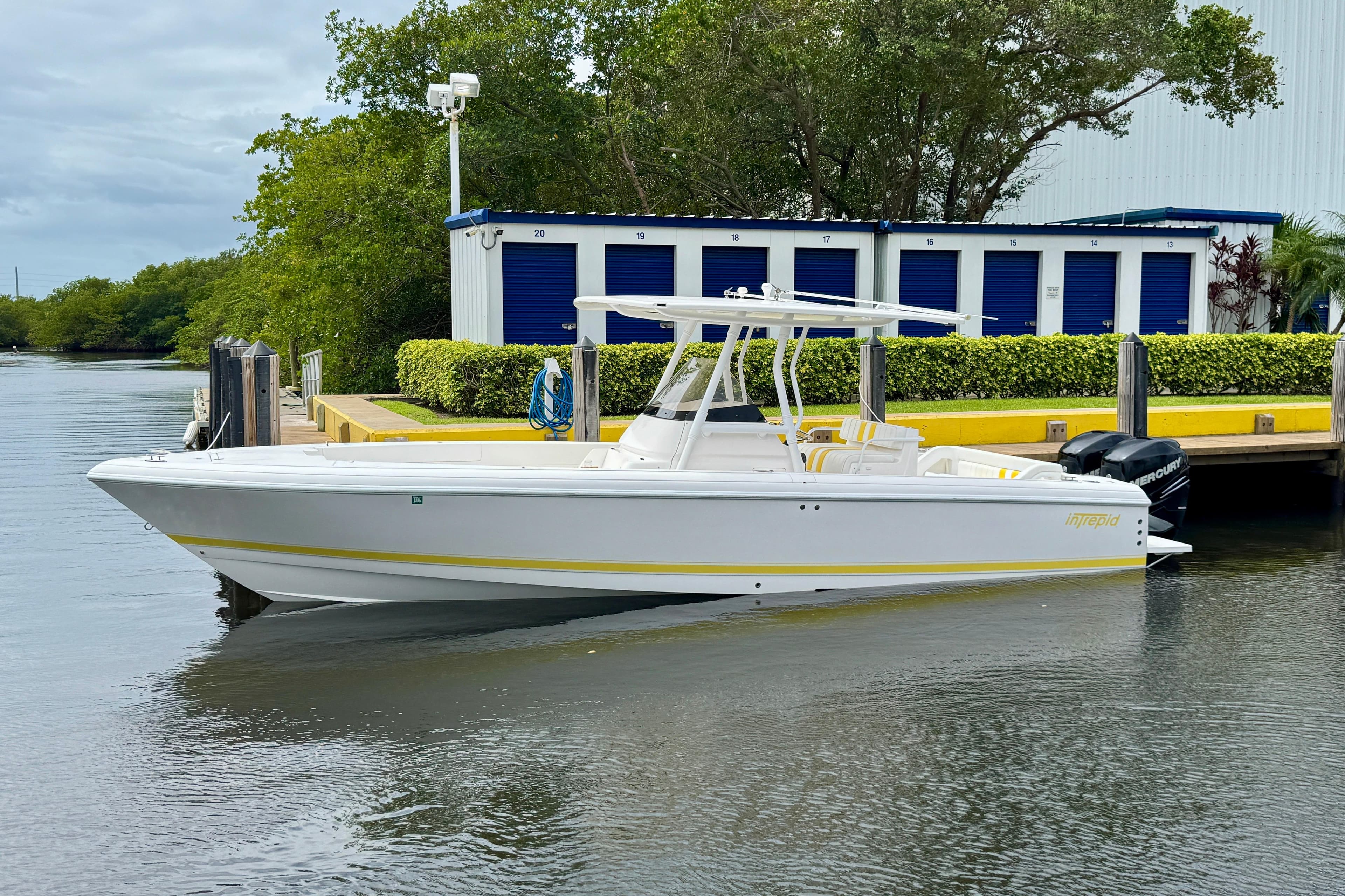 2013 Intrepid 300 Center Console boat docked near storage units.