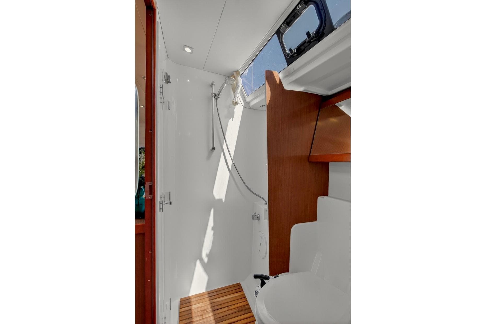 Interior of 2012 Beneteau Oceanis 48 yacht bathroom with shower and wooden accents.