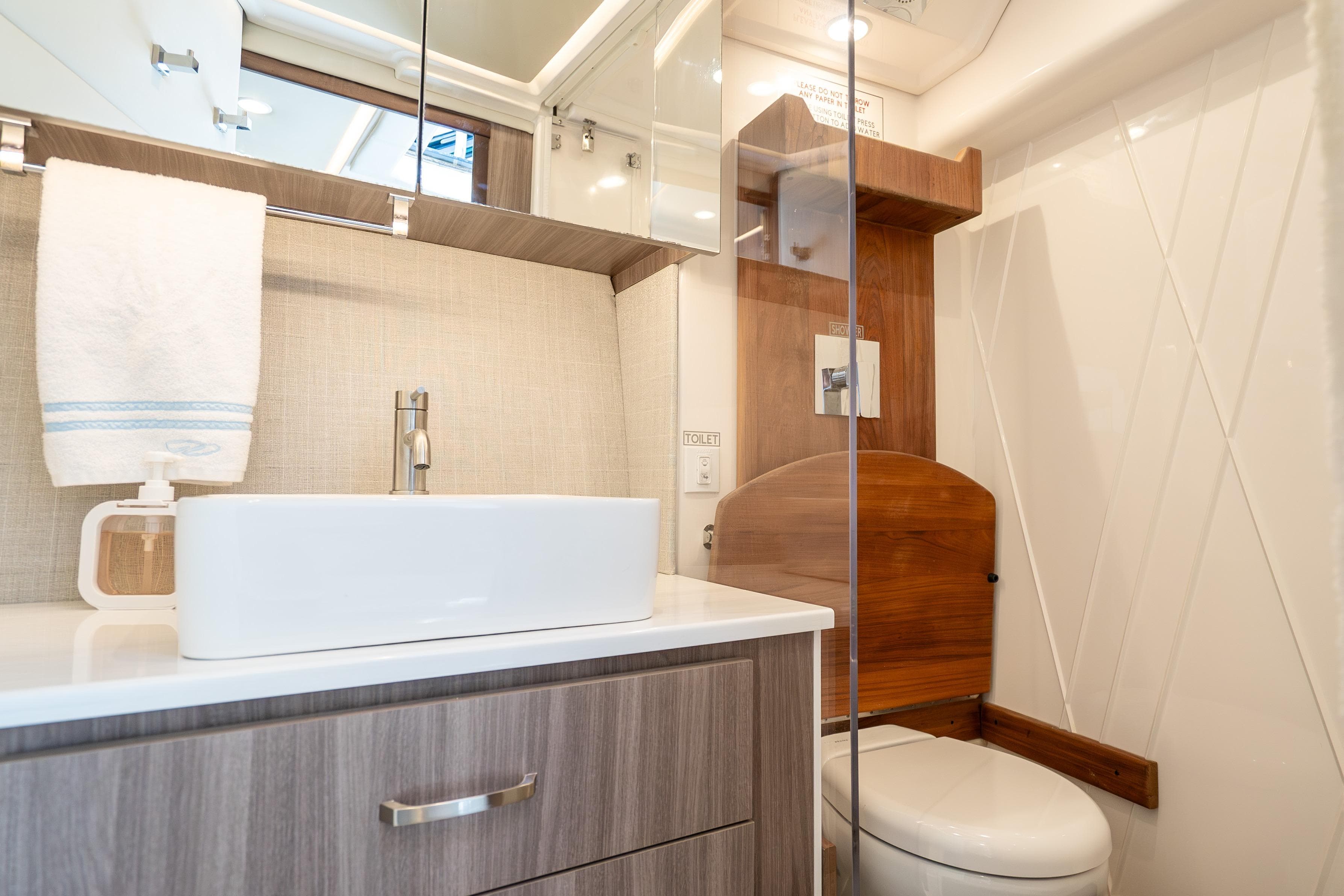 Luxurious bathroom in 2022 Regal 36 Grande Coupe yacht, featuring modern sink and toilet.