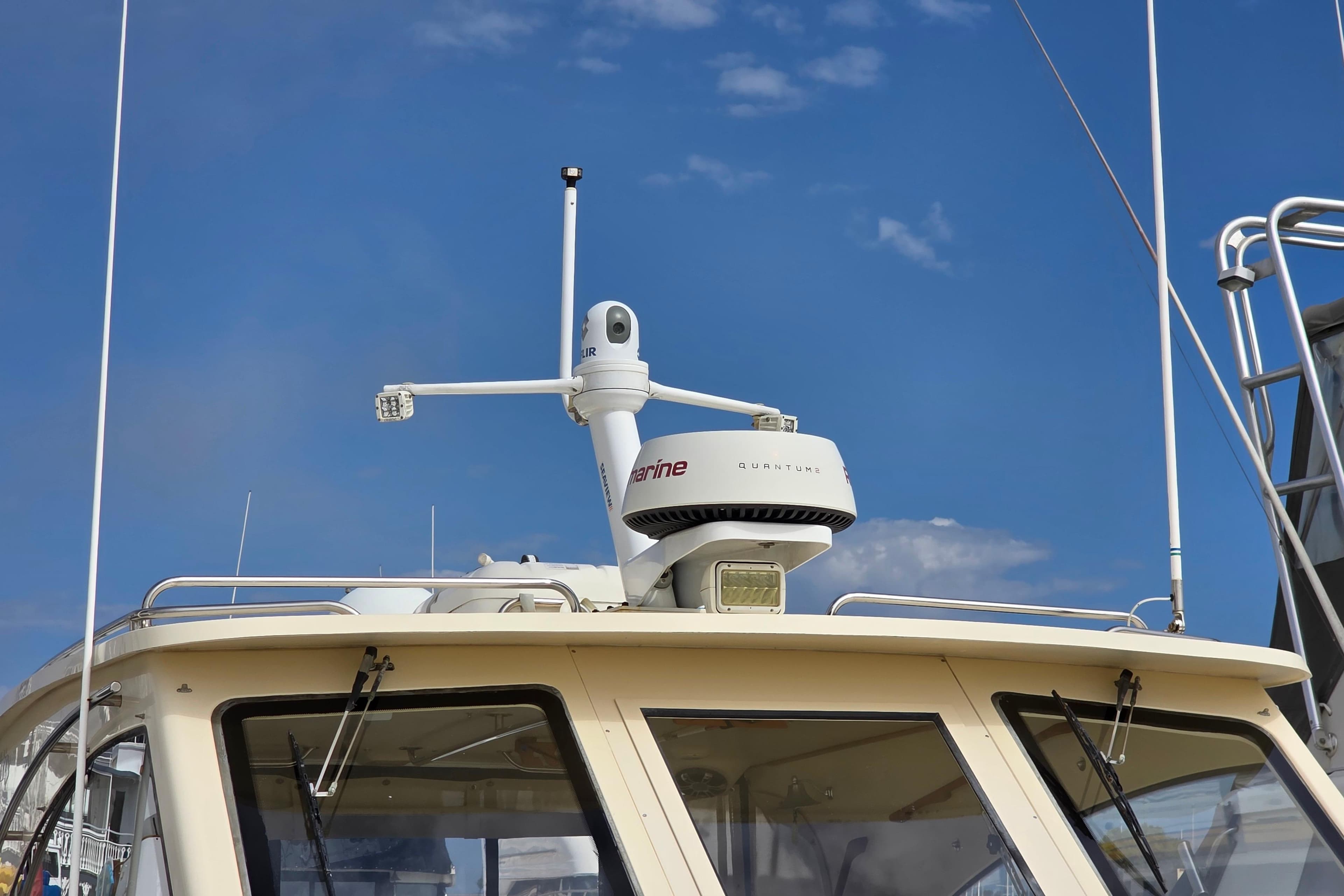 2005 Mainship 34 Pilot Sedan Rum Runner II with radar equipment against blue sky.