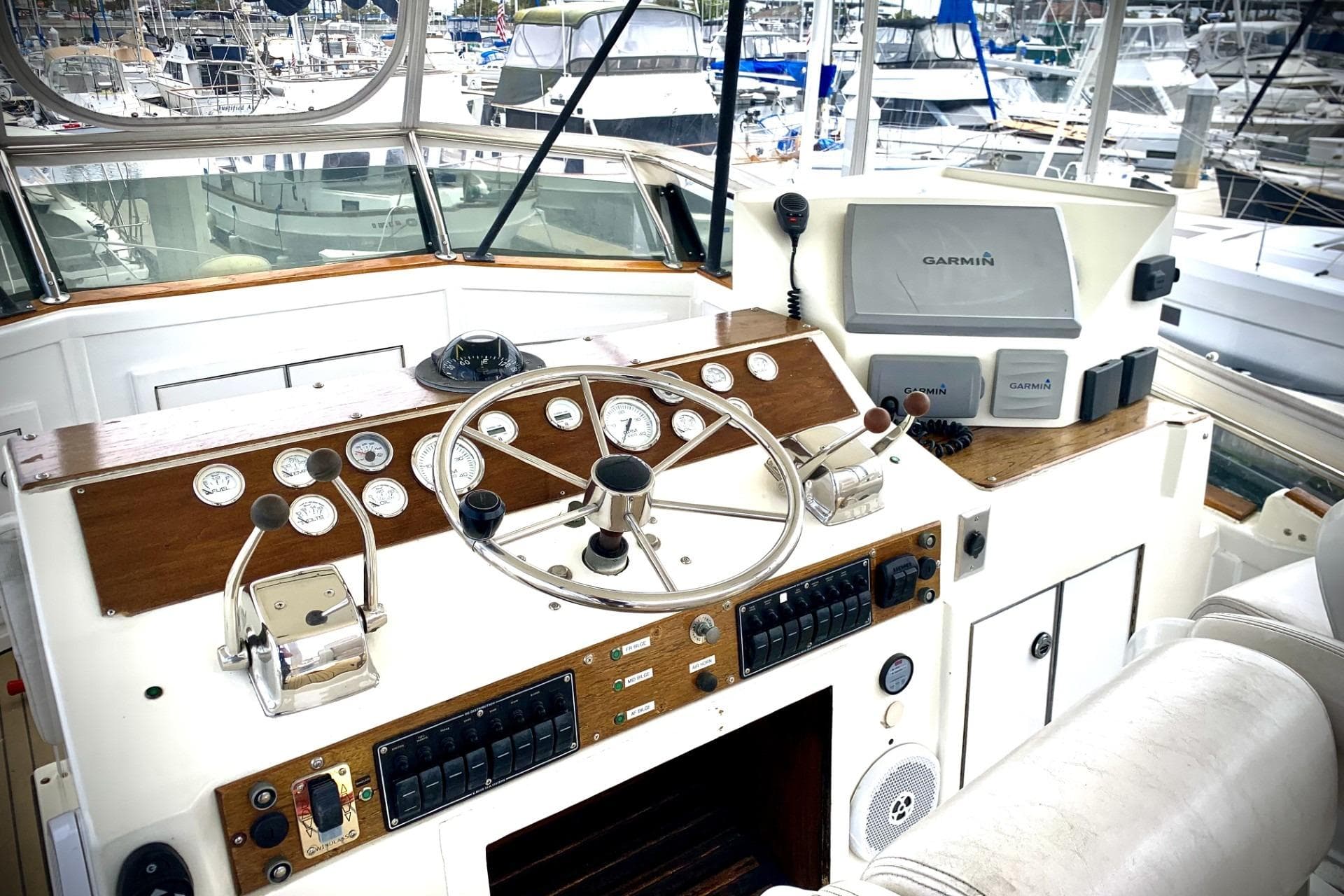 1984 Egg Harbor 48' Flybridge helm with Garmin navigation, gauges, and controls in marina setting.