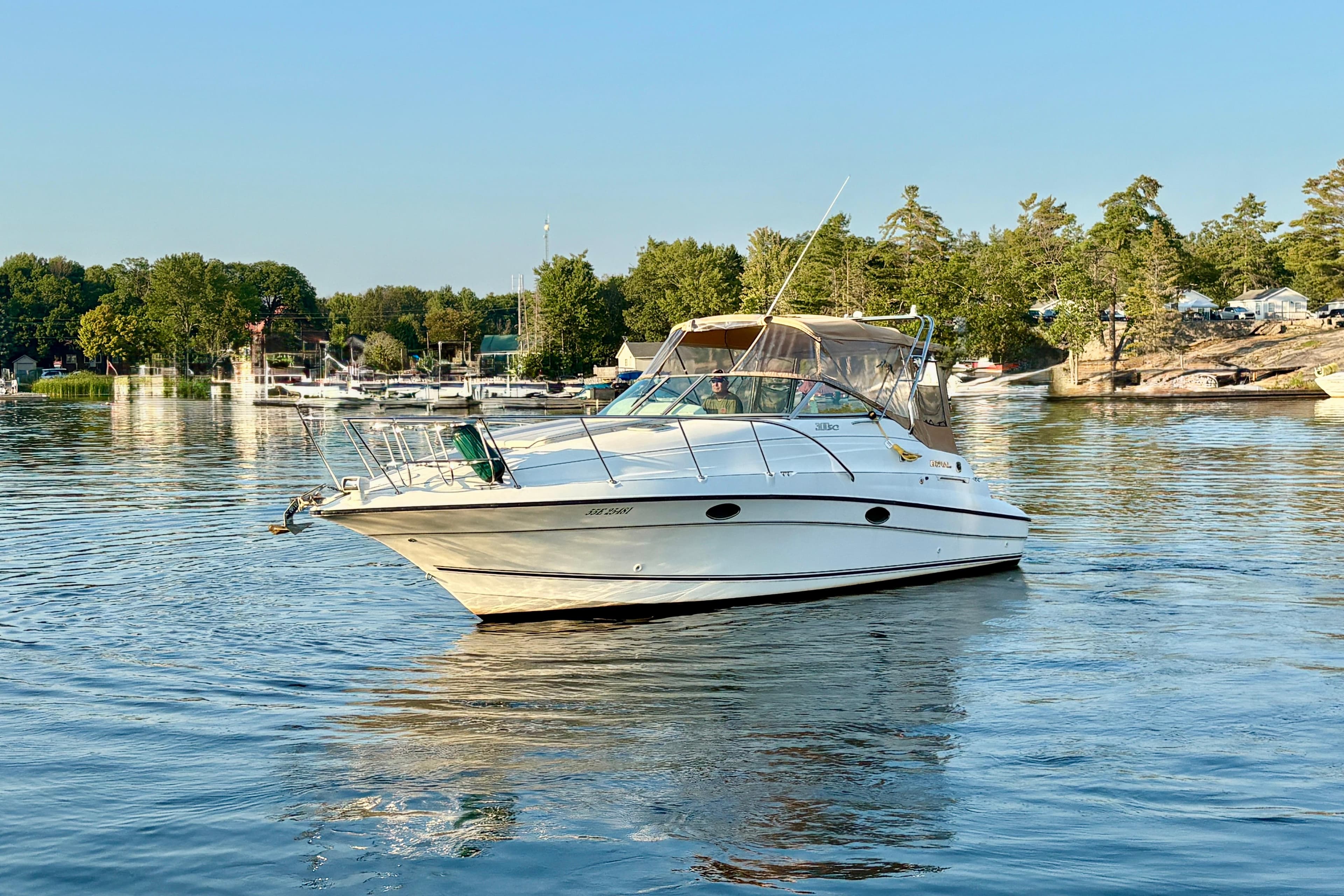 1998 Doral 300SC boat cruising on a serene lake with lush green shoreline.