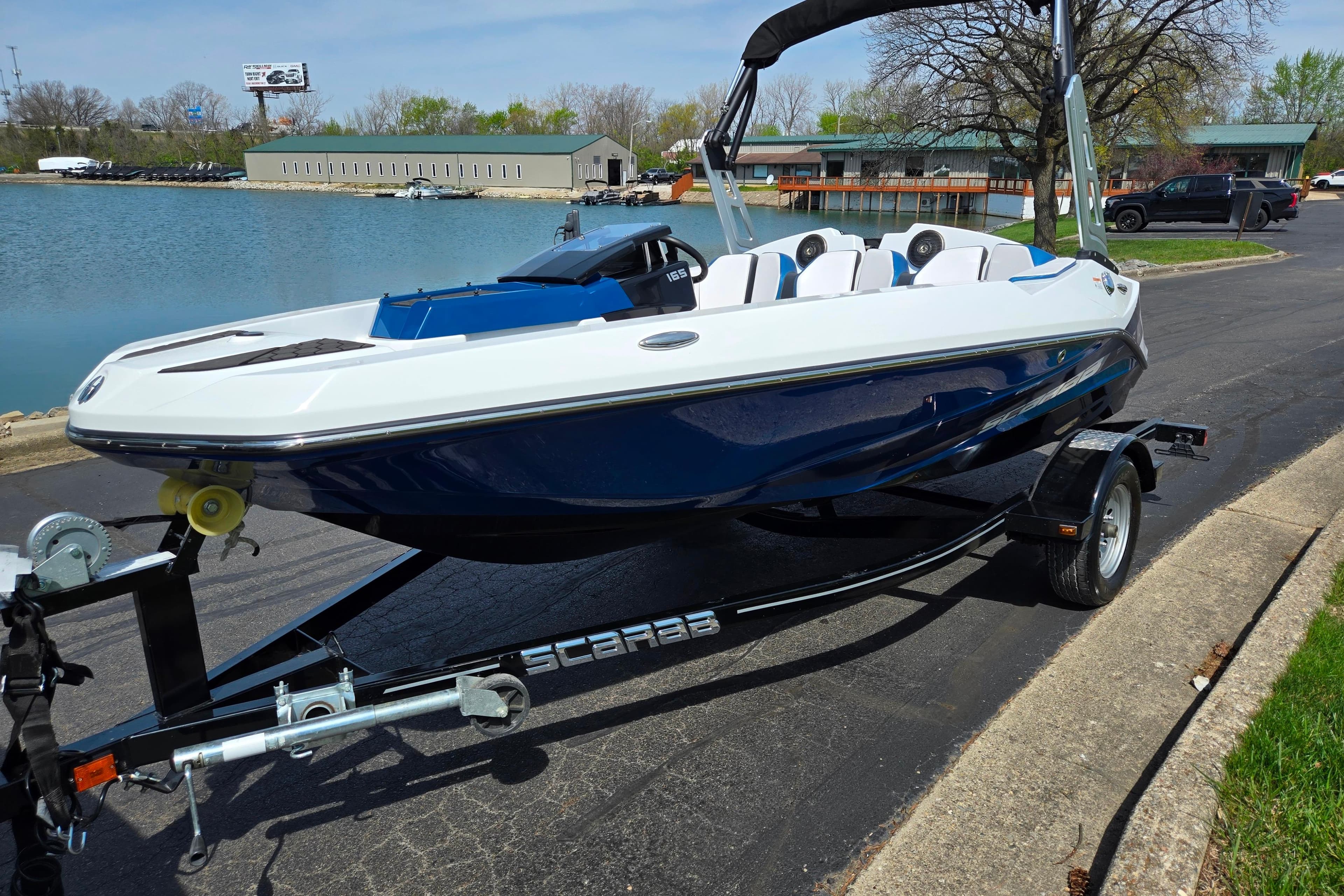 2021 Scarab 165 ID boat on trailer by a lake, showcasing sleek design and modern features.