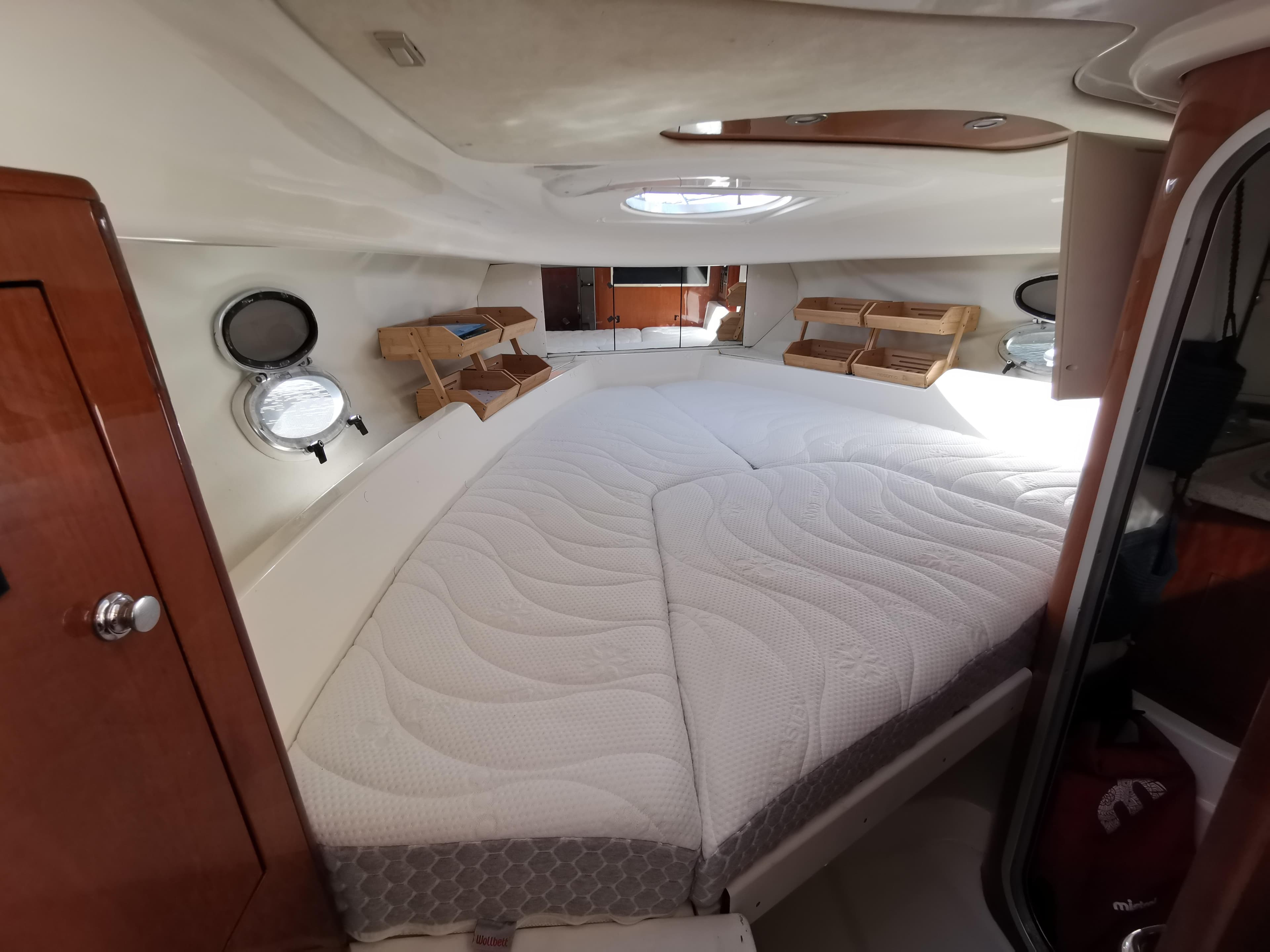 1999 Cranchi CSL 28 cabin interior with bed, wooden shelves, and portholes.