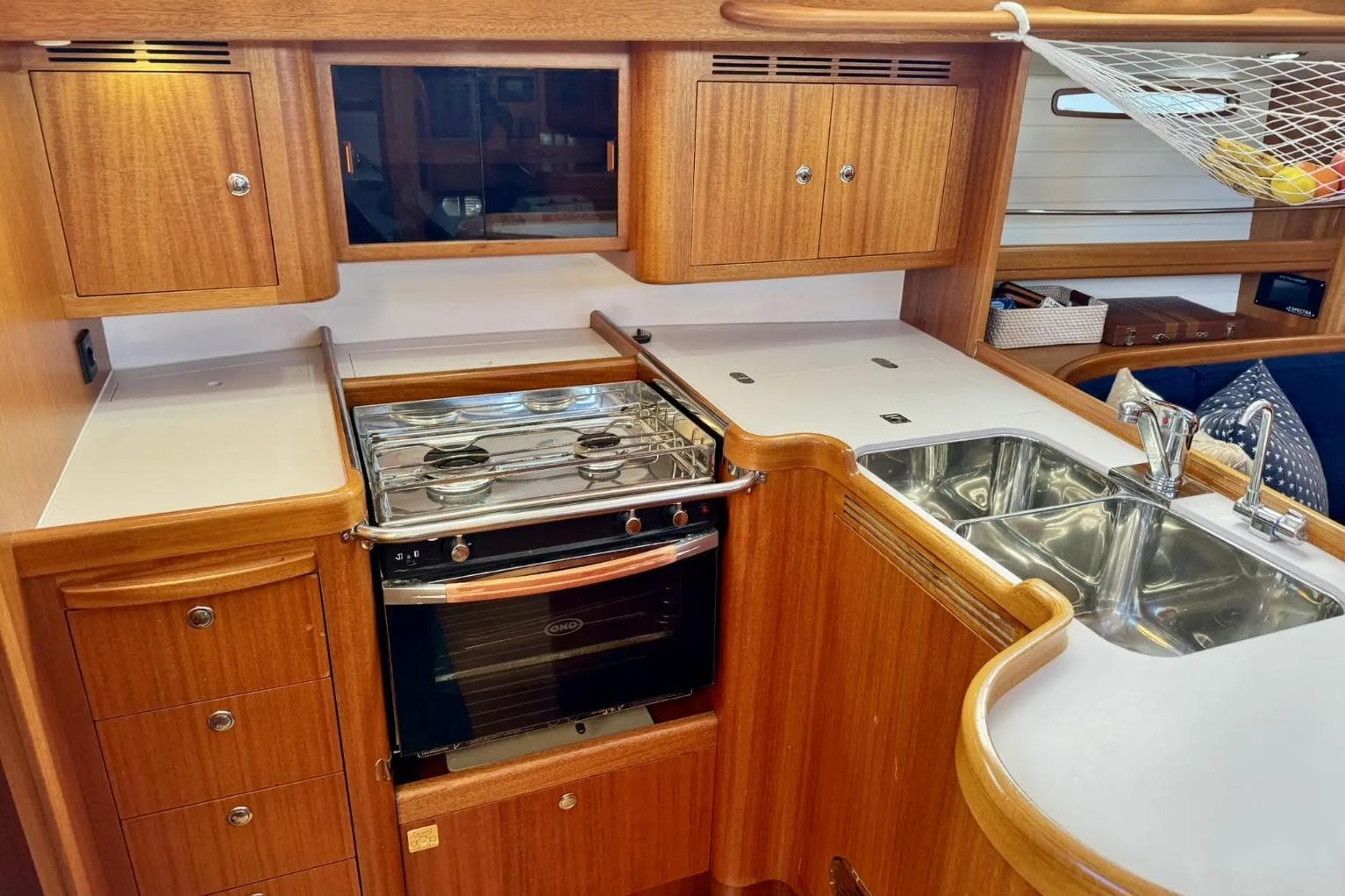2010 Arcona 430 yacht kitchen with stove, sink, and wooden cabinetry.